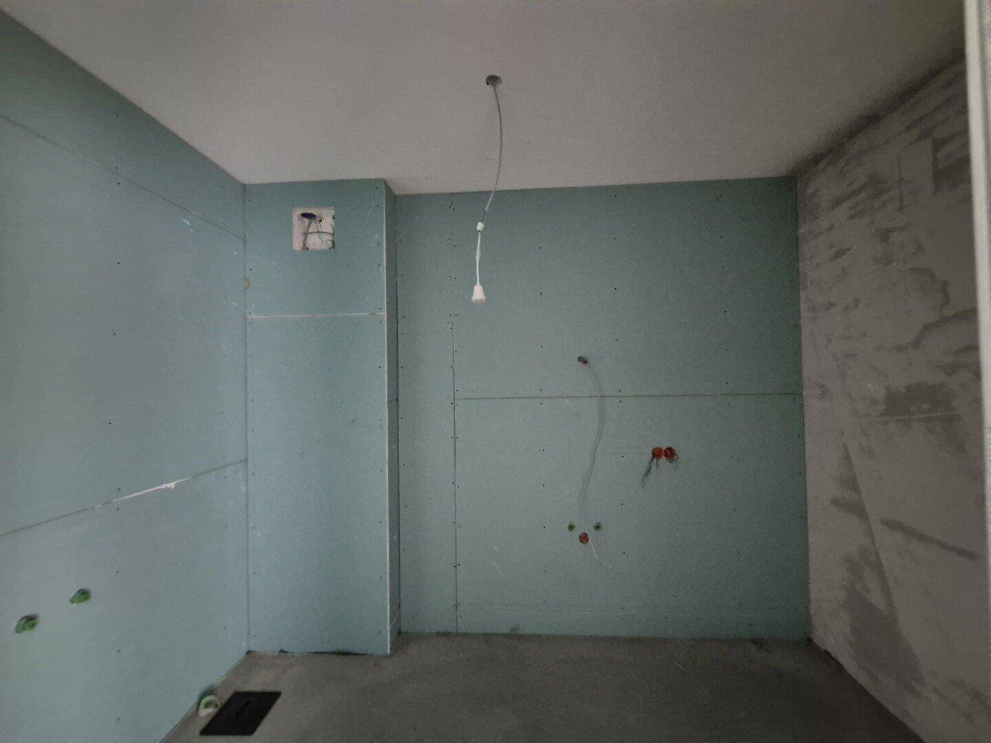 Rohbau-Badezimmer mit feuchtigkeitsbeständigen Wänden und vorbereiteten Anschlüssen für Sanitärinstallationen.