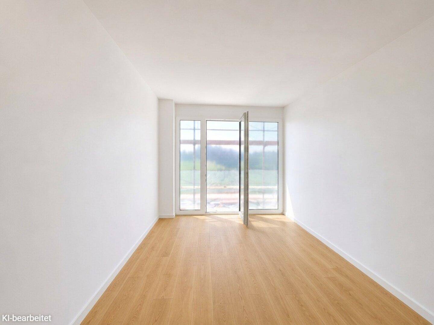 Heller, leerer Raum mit großen Fenstern und Blick ins Grüne, ausgestattet mit Laminatboden.