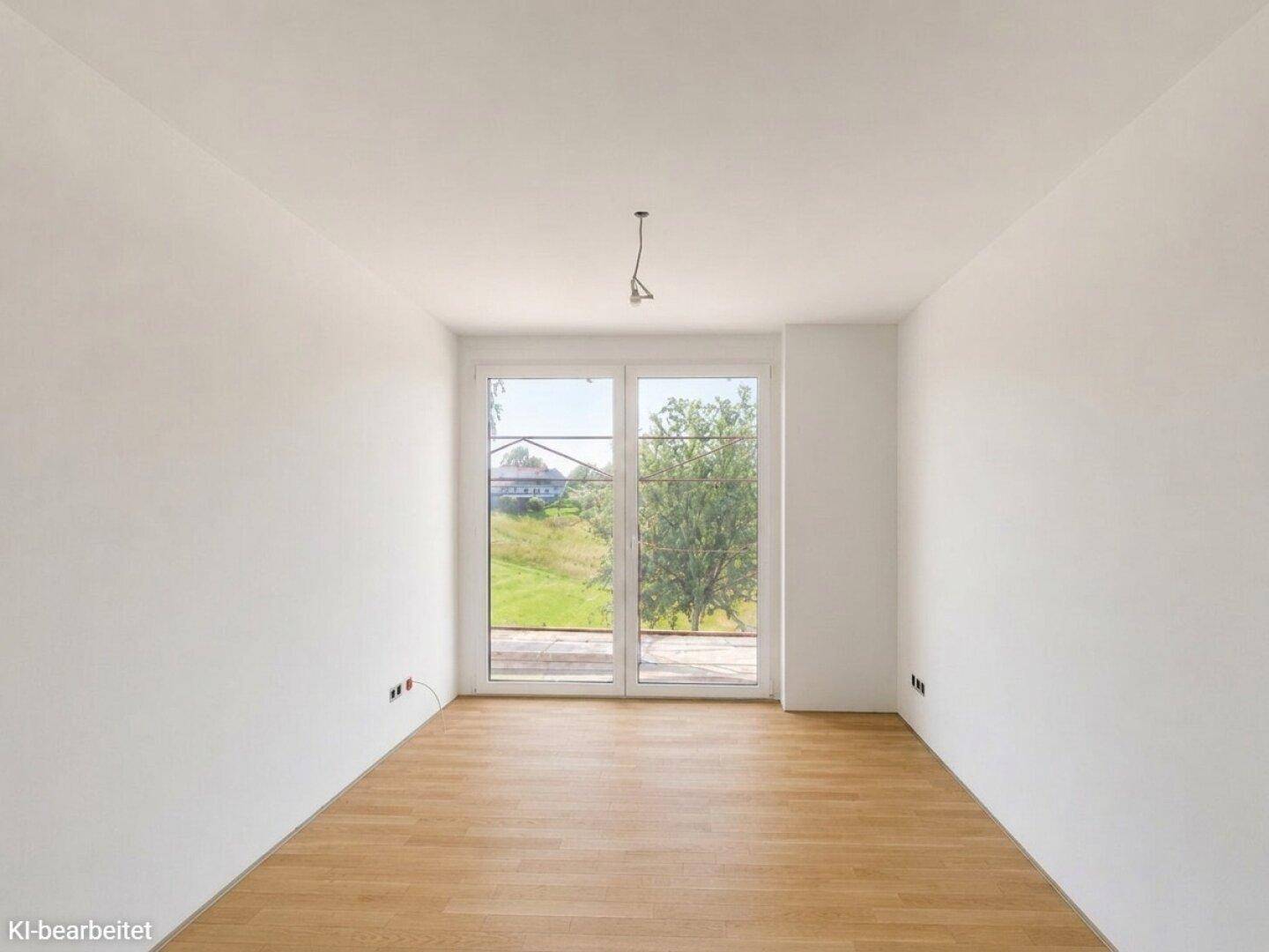 Helles, leeres Zimmer mit Eichenparkettboden und großen Fenstern mit Blick ins Grüne.