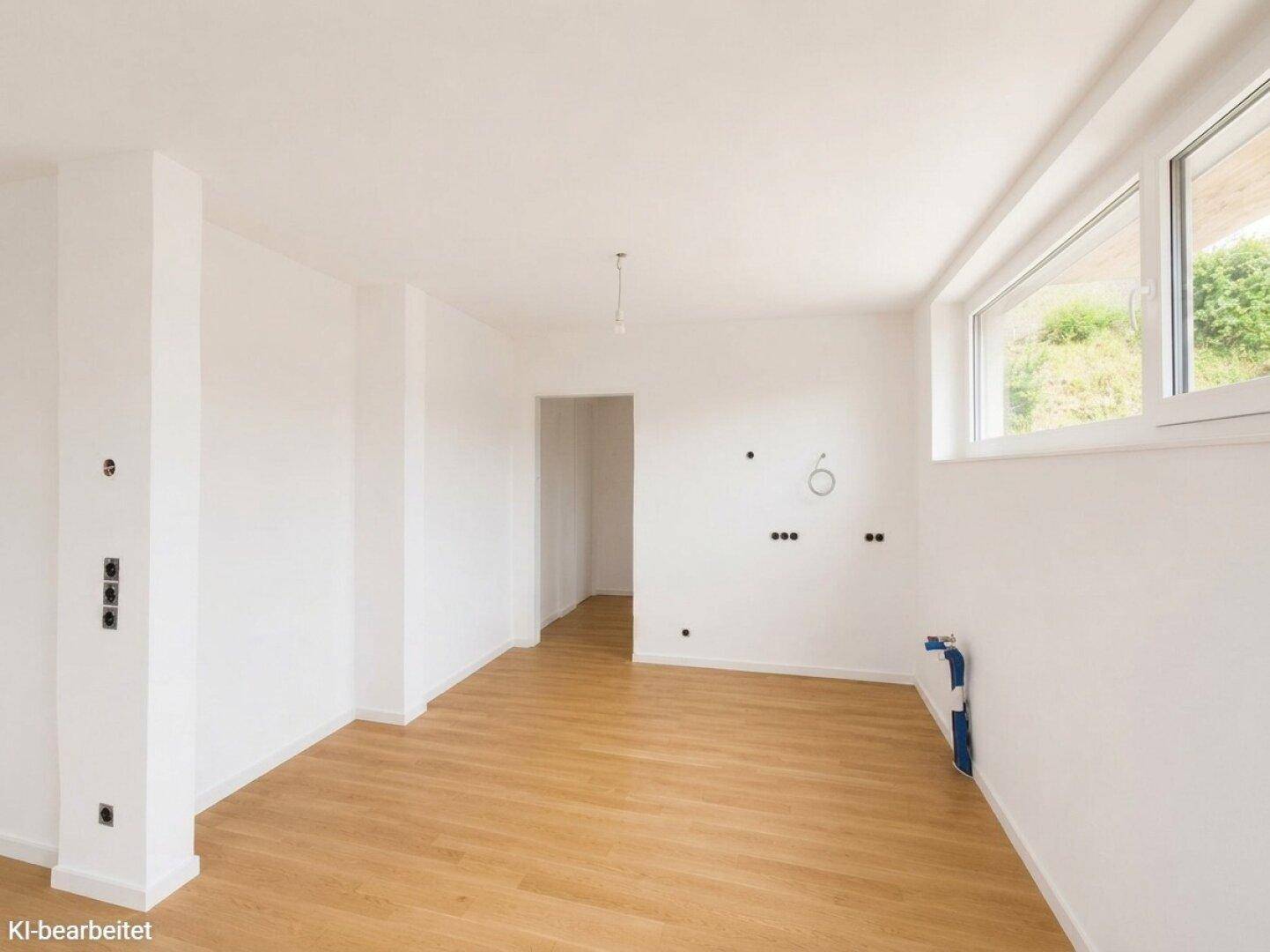 Leerer Raum mit Holzboden, weißen Wänden und einem Fenster, vorbereitet für weitere Installationen.