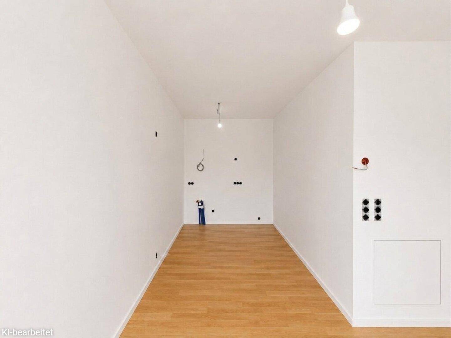 Unfertige Küche mit vorbereiteten Anschlüssen und hellem Holzboden, bereit für den Einbau.