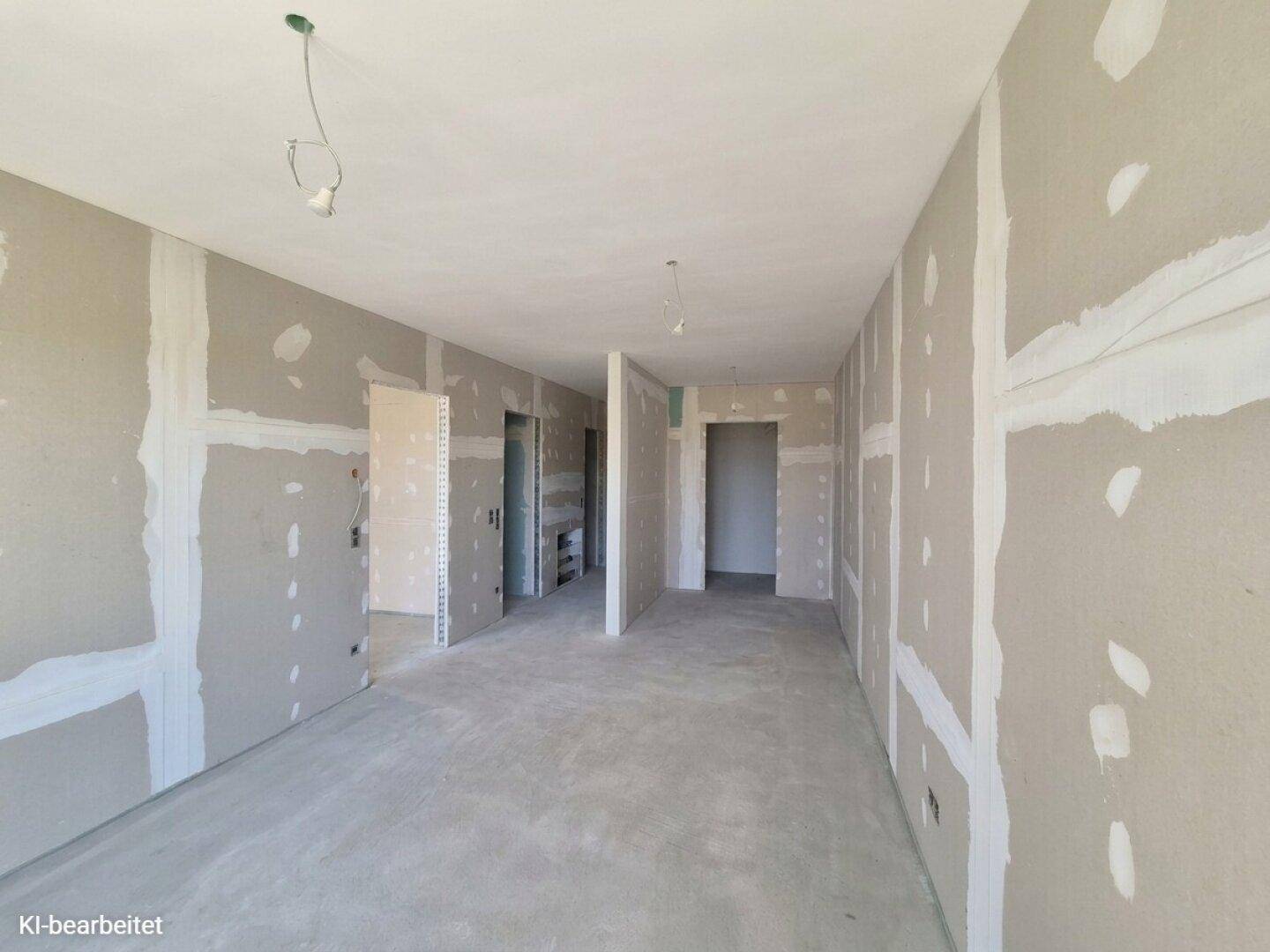 Innenraum im Rohbauzustand mit Trockenbauwänden und Betonboden, bereit für den weiteren Ausbau.
