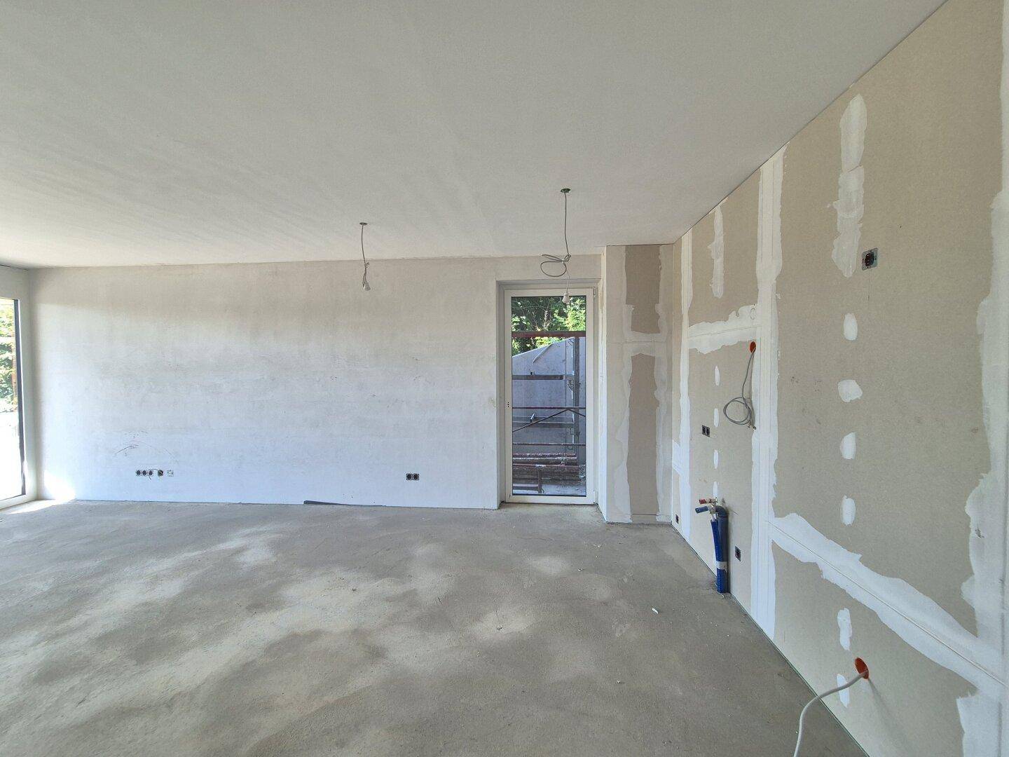 Rohbauküche mit Betonboden und vorbereiteten Wänden für die Installation der Kücheneinrichtung.