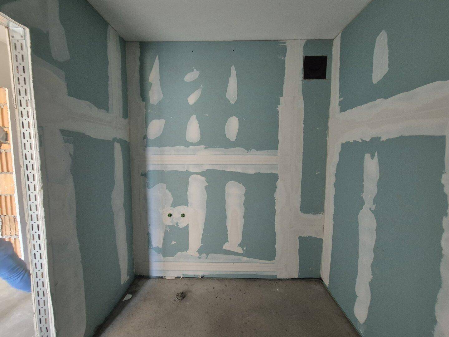 Badezimmer im Rohbau mit feuchtigkeitsbeständigen Wänden und vorbereiteten Anschlüssen für Sanitäranlagen.