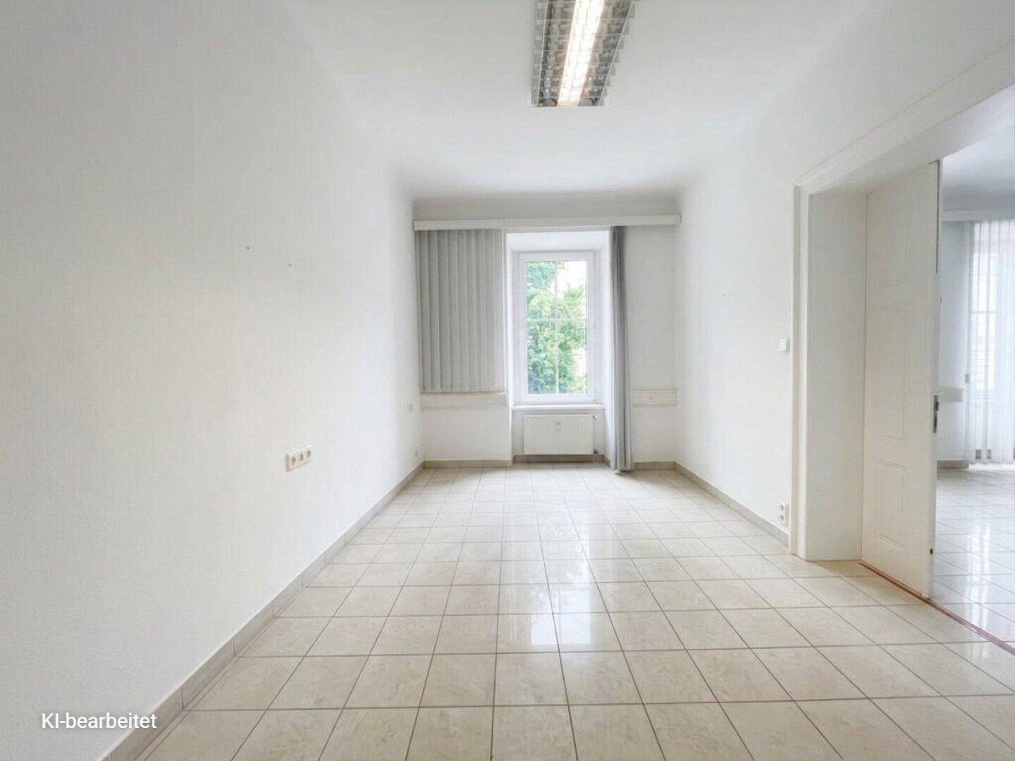 Heller Büroraum mit Fliesenboden, großem Fenster und Deckenleuchten, ideal für verschiedene Nutzungen.
