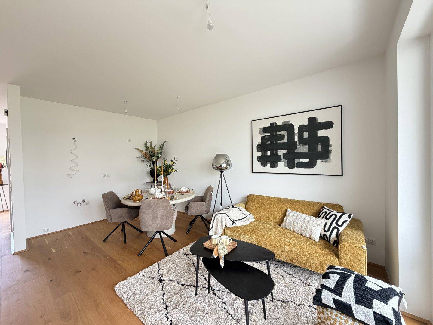 Offener Wohn- und Essbereich mit gelbem Sofa, modernem Esstisch und Holzboden.