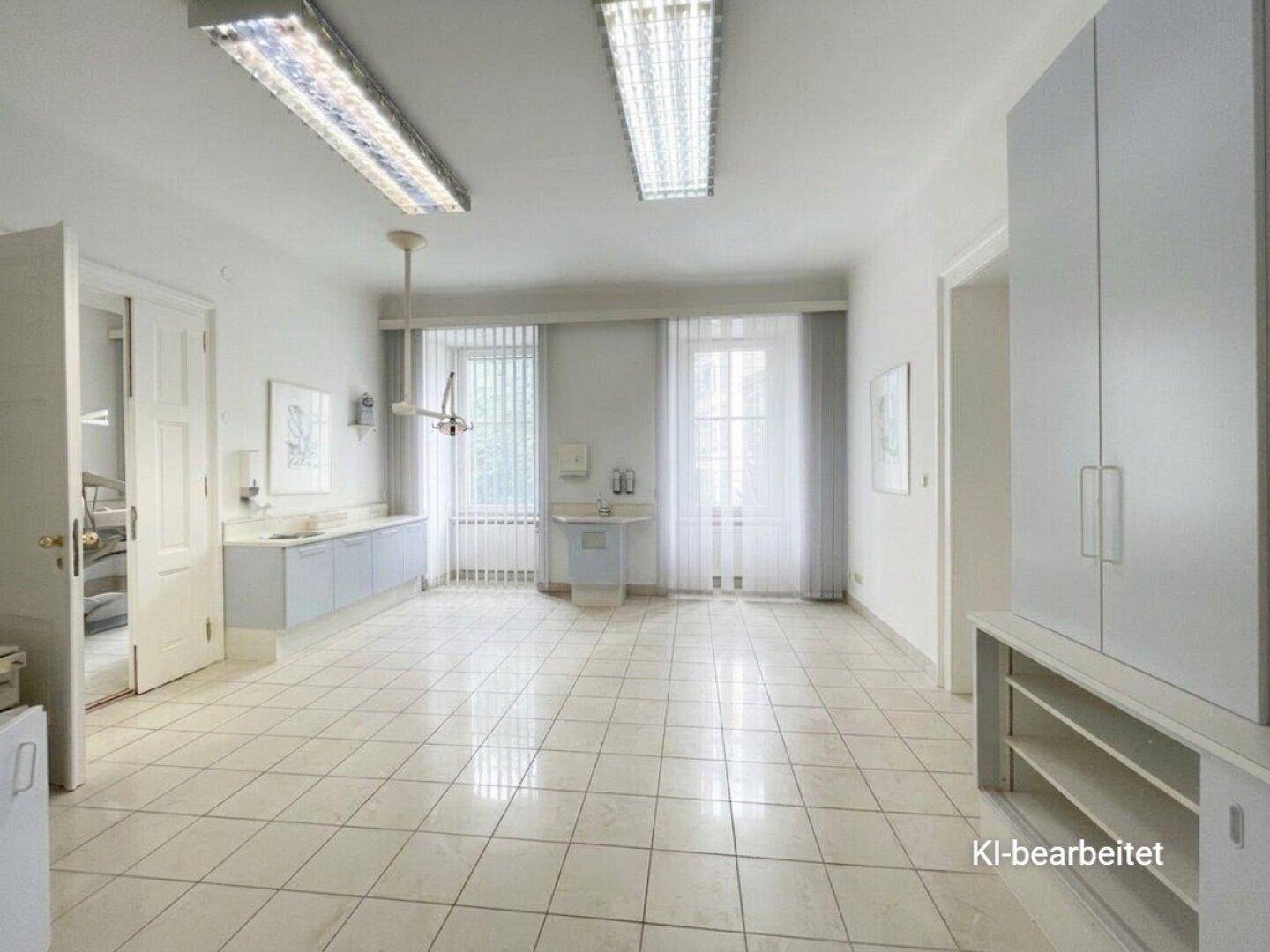 Geräumiger Behandlungsraum mit Fliesenboden, medizinischen Geräten und großen Fenstern für viel Licht.