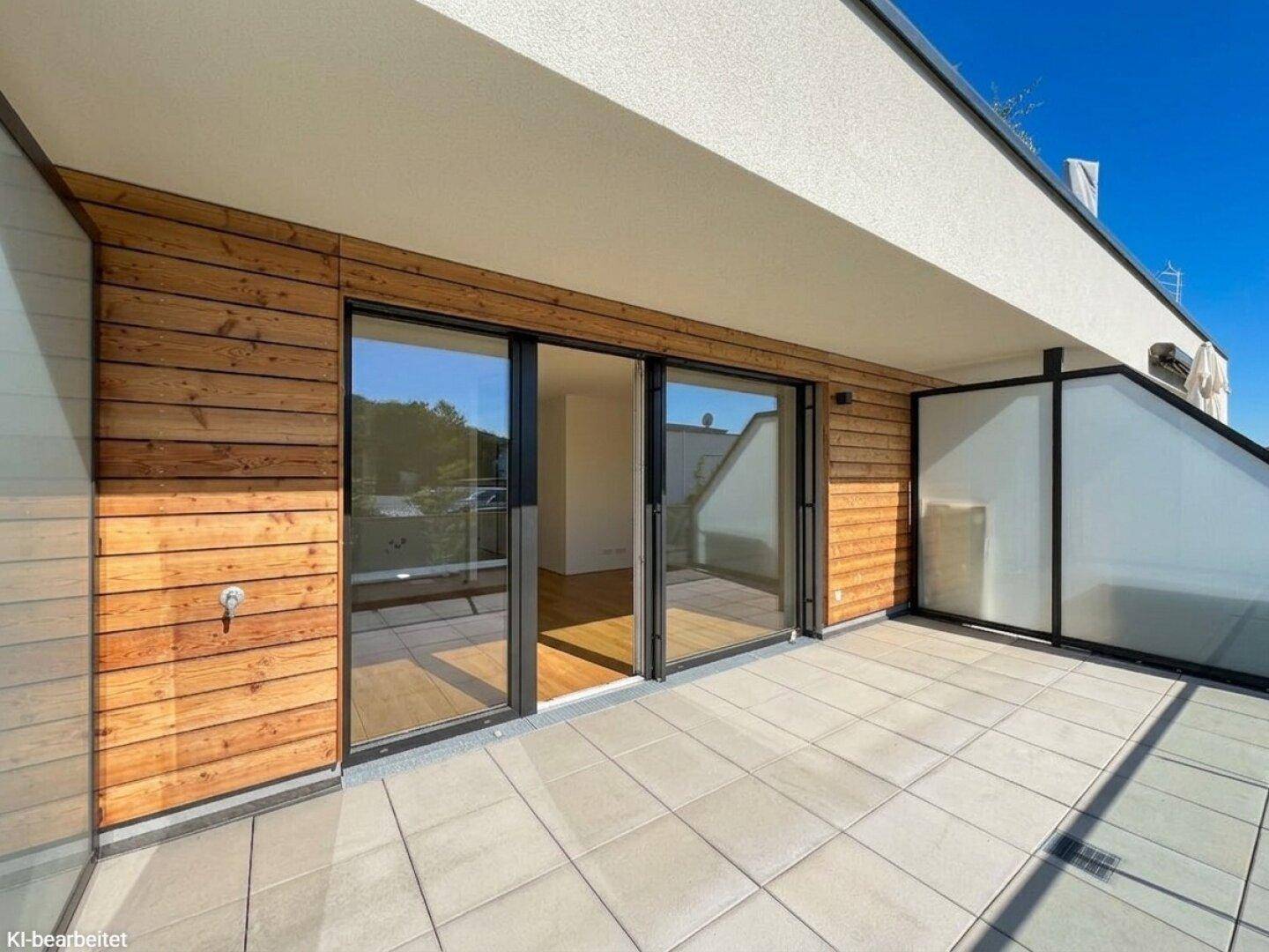 Geräumiger Balkon mit Holzverkleidung und großen Glasschiebetüren zum Innenbereich.