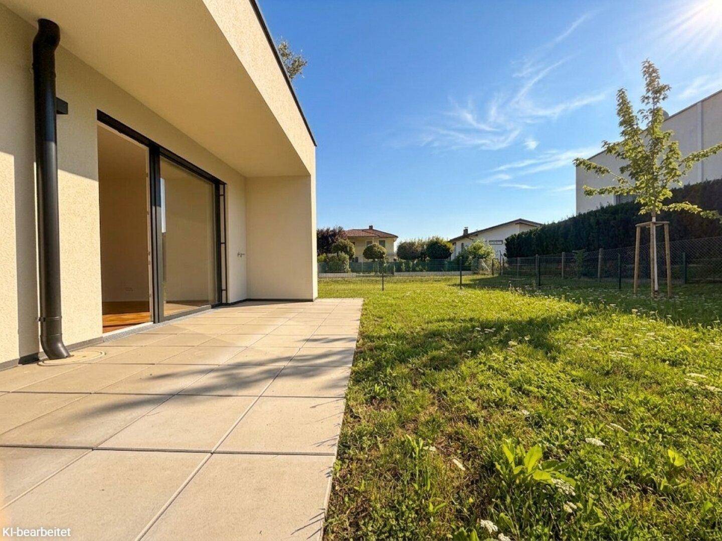 Großzügige, gepflasterte Terrasse neben dem Haus mit Rasenfläche und sonnigem Ausblick.