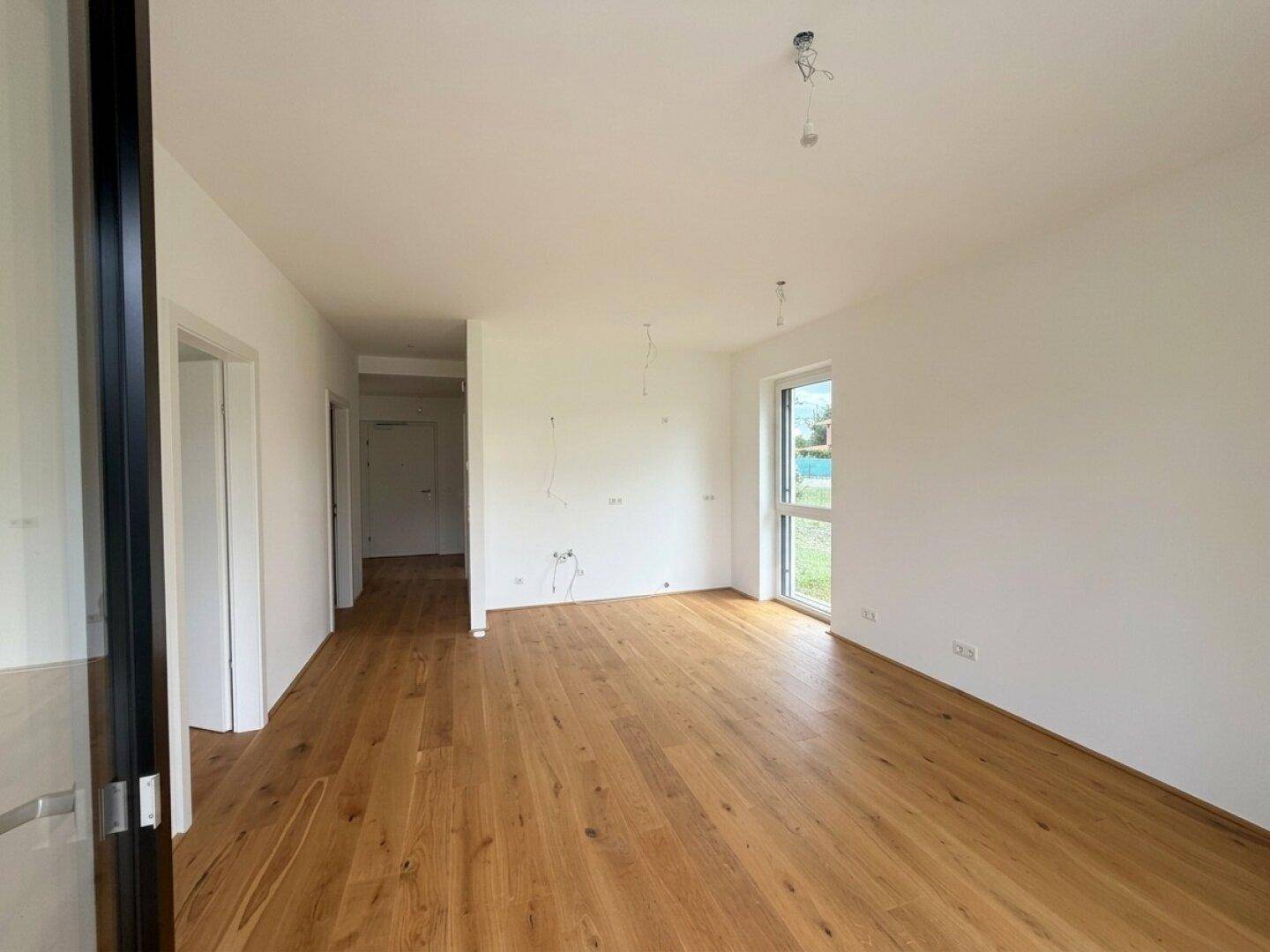 Heller, leerer Raum mit neuem Holzfußboden und weißen Wänden, bereit zum Einzug.