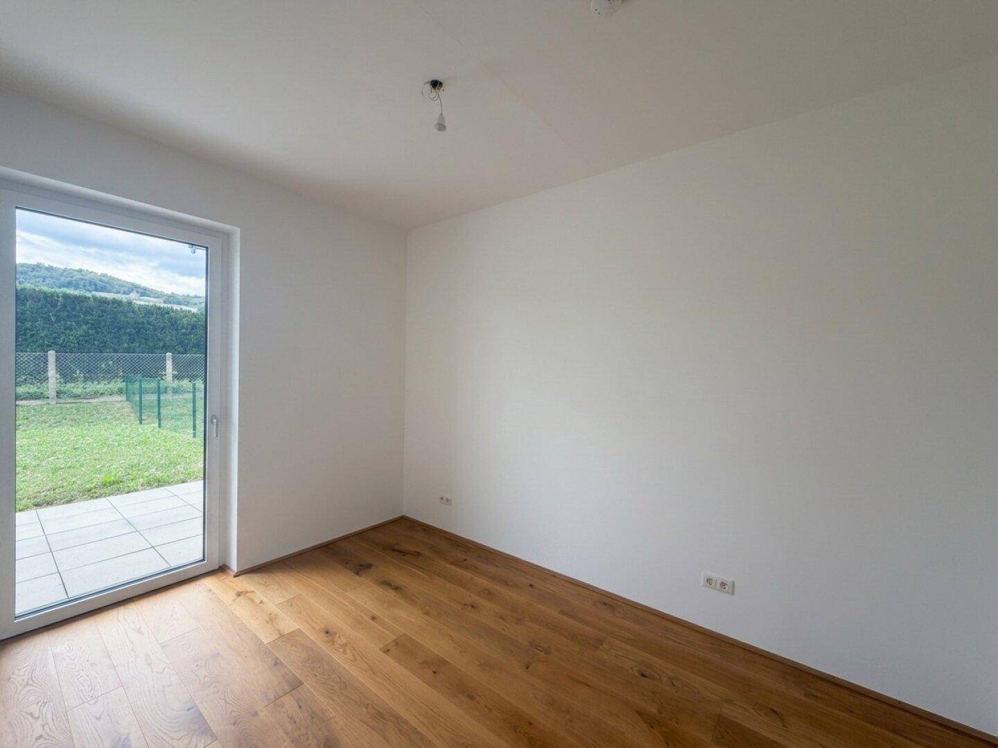 Geräumiger, heller Raum mit Holzboden und direktem Zugang zur Terrasse und zum Garten.