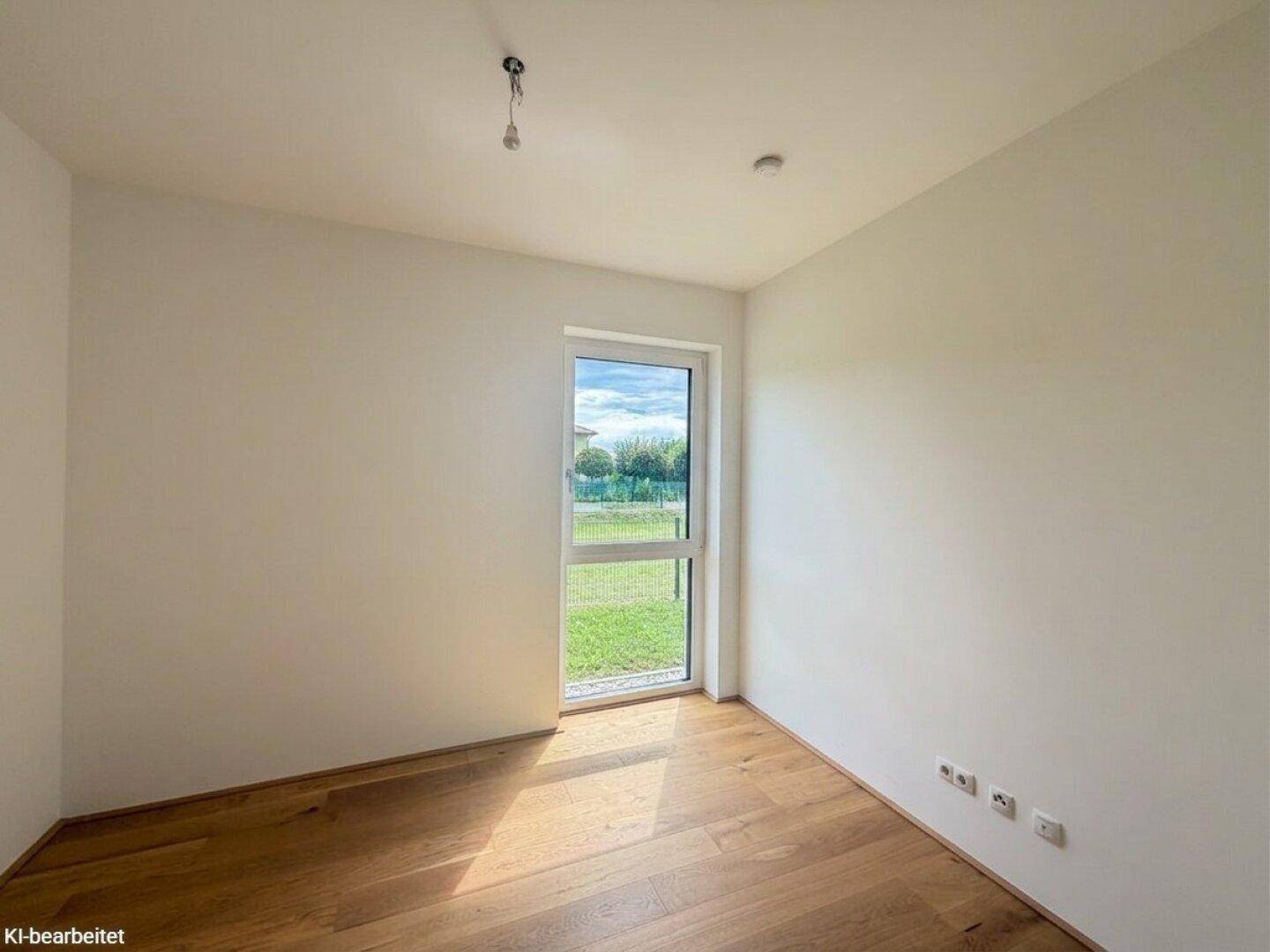 Helles Schlafzimmer mit Holzboden und einem Fenster, das viel Tageslicht hereinlässt.