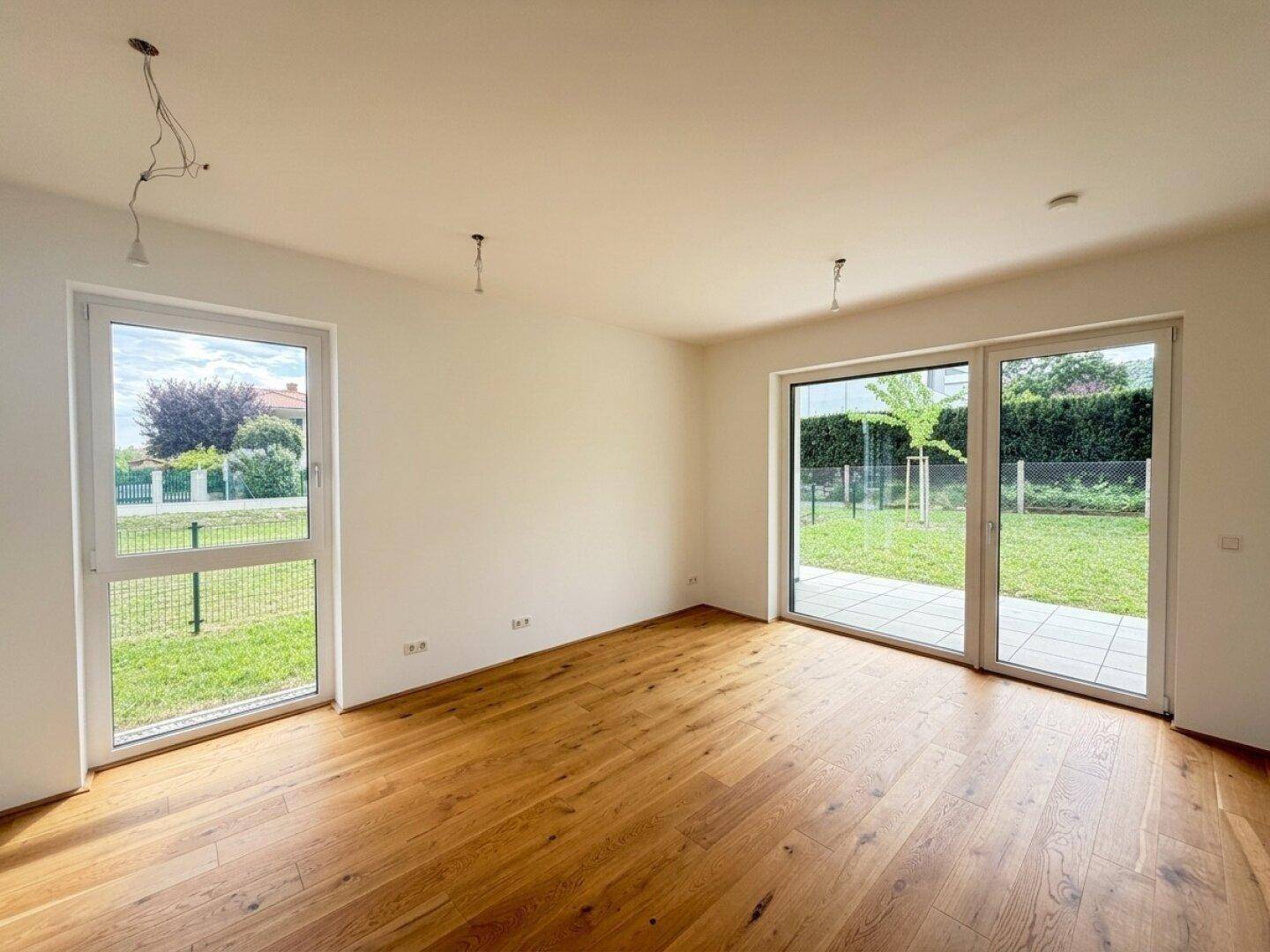 Lichtdurchfluteter Wohnraum mit Holzboden und großen Schiebetüren zum Gartenbereich.