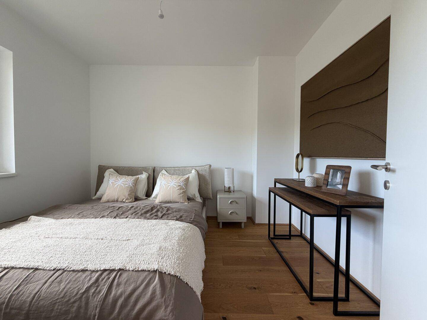 Helles Schlafzimmer mit Holzboden, einem Doppelbett und moderner Dekoration sowie natürlichem Lichteinfall.