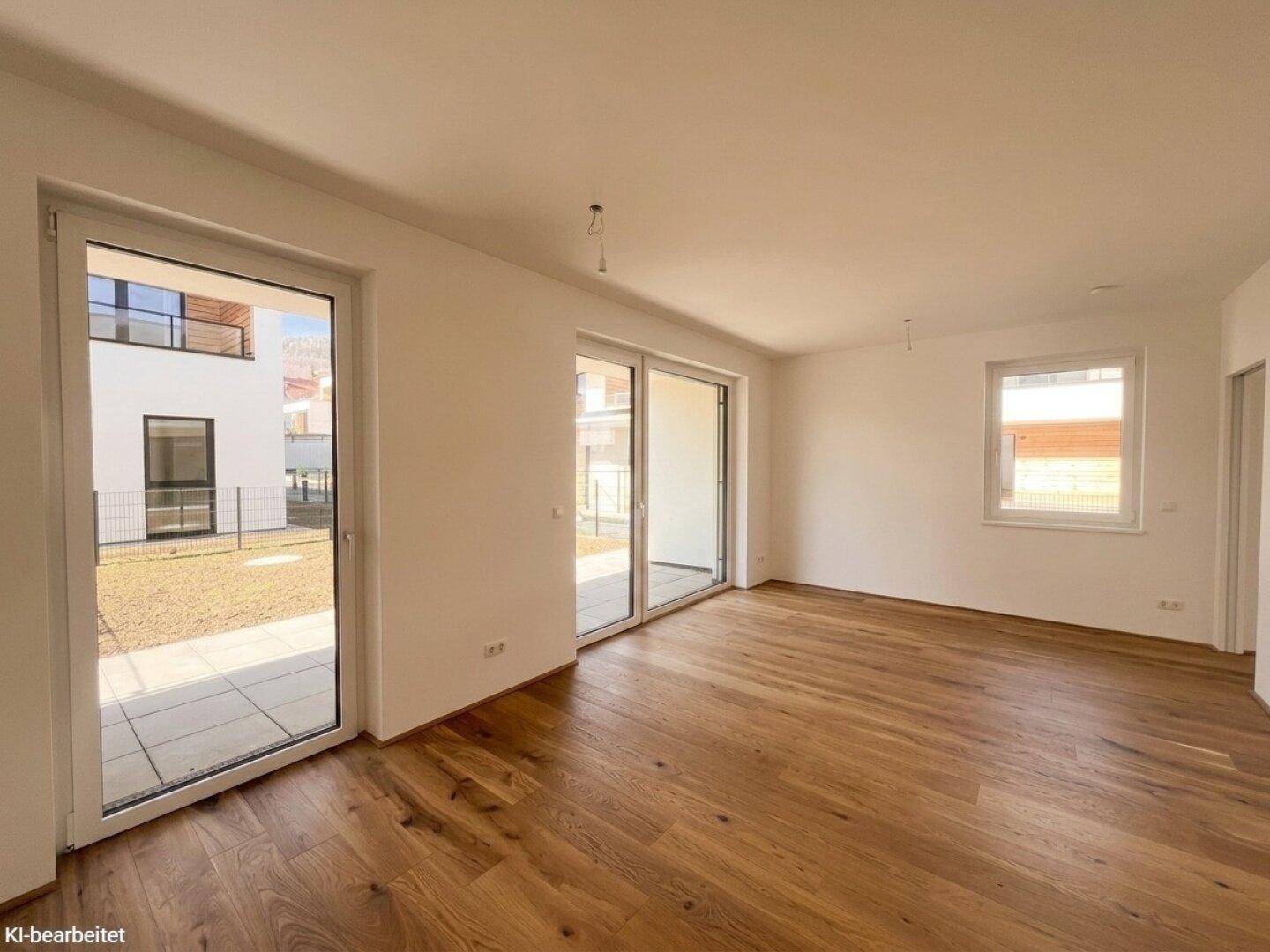 Geräumiges, unmöbliertes Zimmer mit Holzboden und großen Fenstern, die viel Tageslicht hereinlassen.