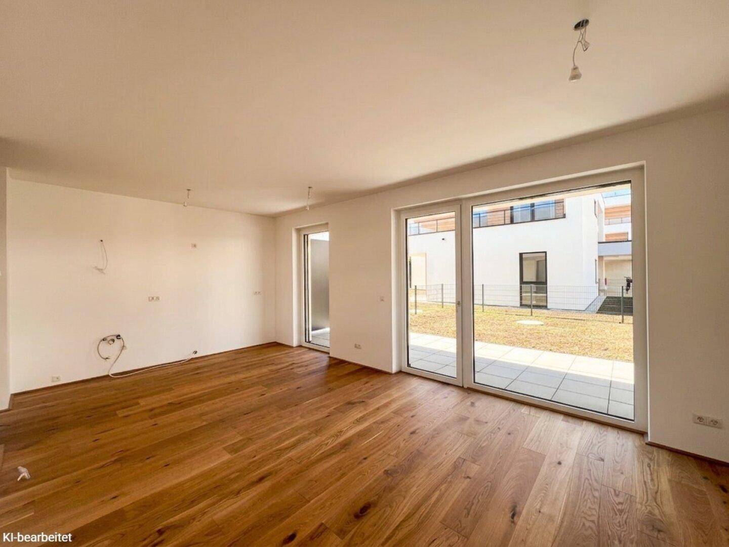 Heller, leerer Raum mit Holzboden und breiten Schiebetüren, die zu einer Terrasse führen.