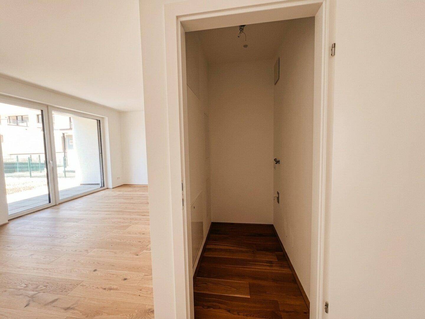 Praktischer Hauswirtschaftsraum mit Anschlüssen und Holzboden, angrenzend an den Wohnbereich.