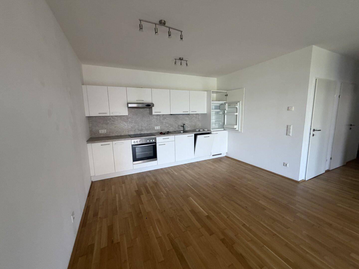 Moderne Einbauküche mit weißen Schränken und Holzfußboden in einem offenen Wohnbereich integriert.