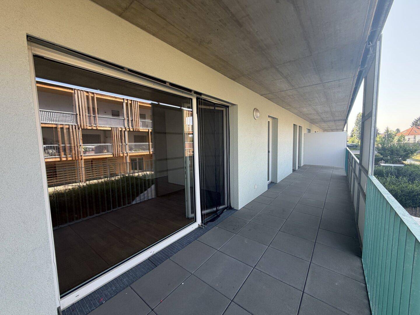 Geräumiger Balkon mit Fliesenboden und Blick auf die Fassade des gegenüberliegenden Gebäudes.