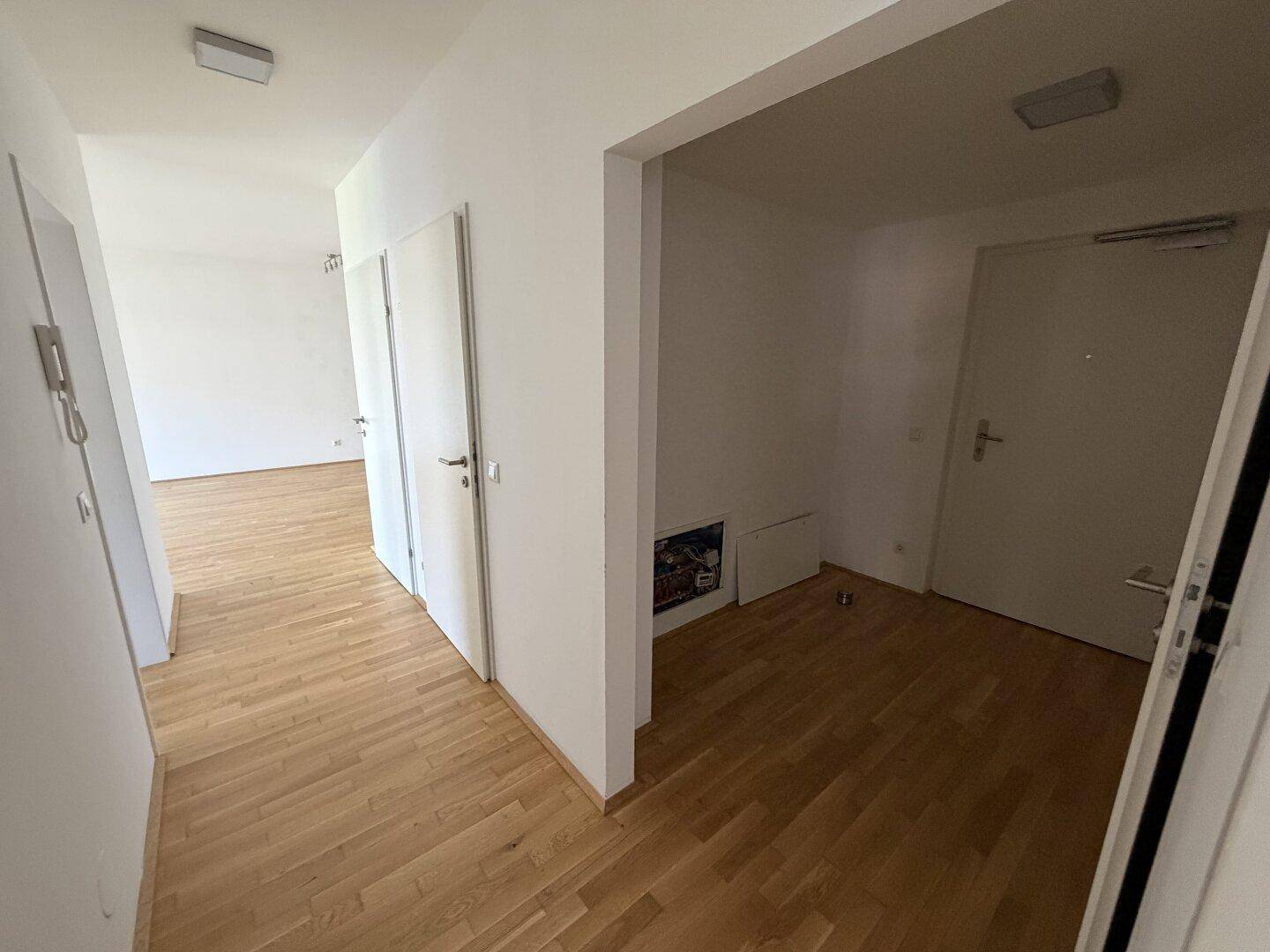 Heller Flur mit Holzparkettboden, der zu verschiedenen Räumen der Wohnung führt.