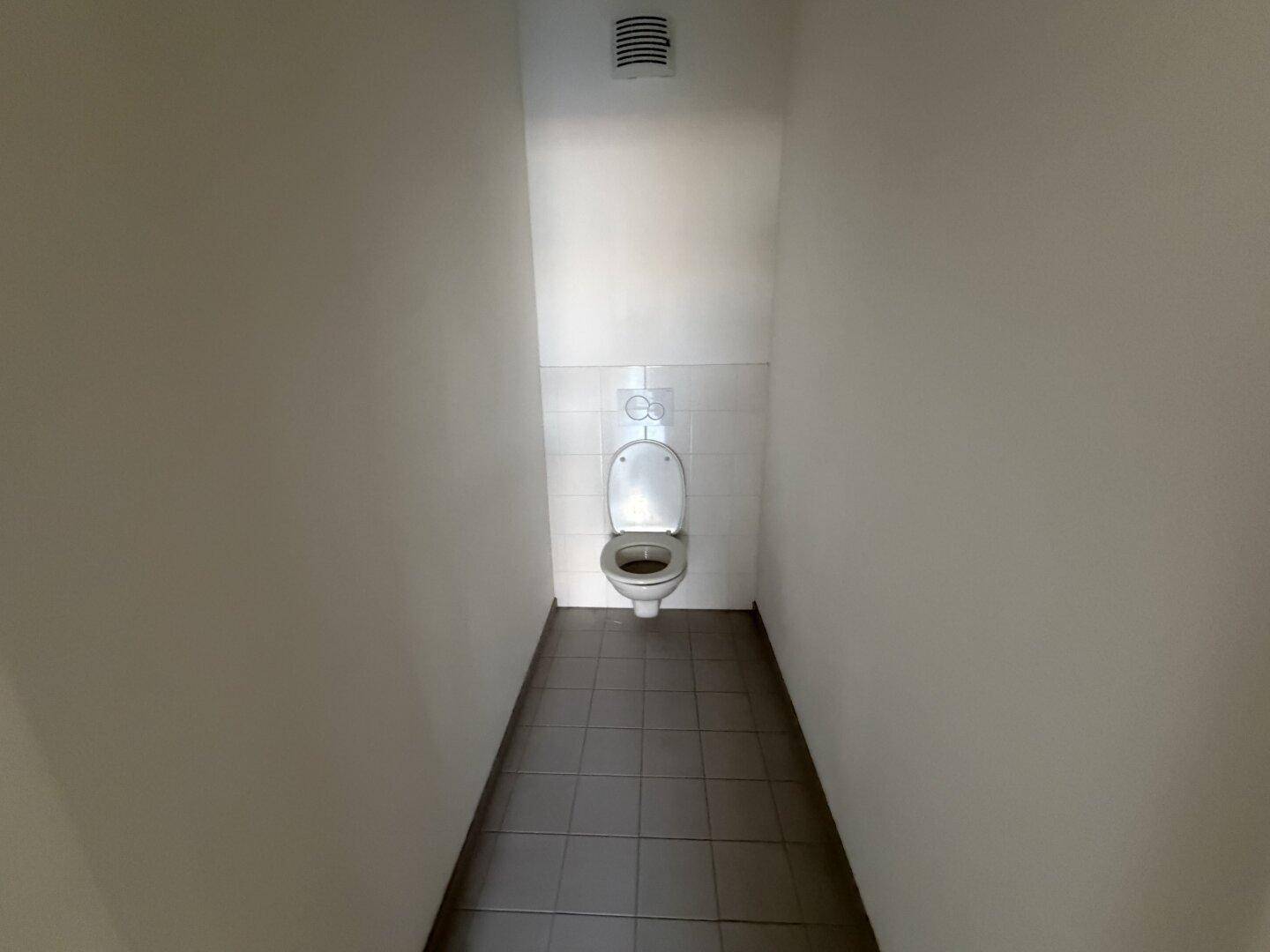Separates WC mit Wand-WC und Fliesenboden, funktional und sauber gestaltet.