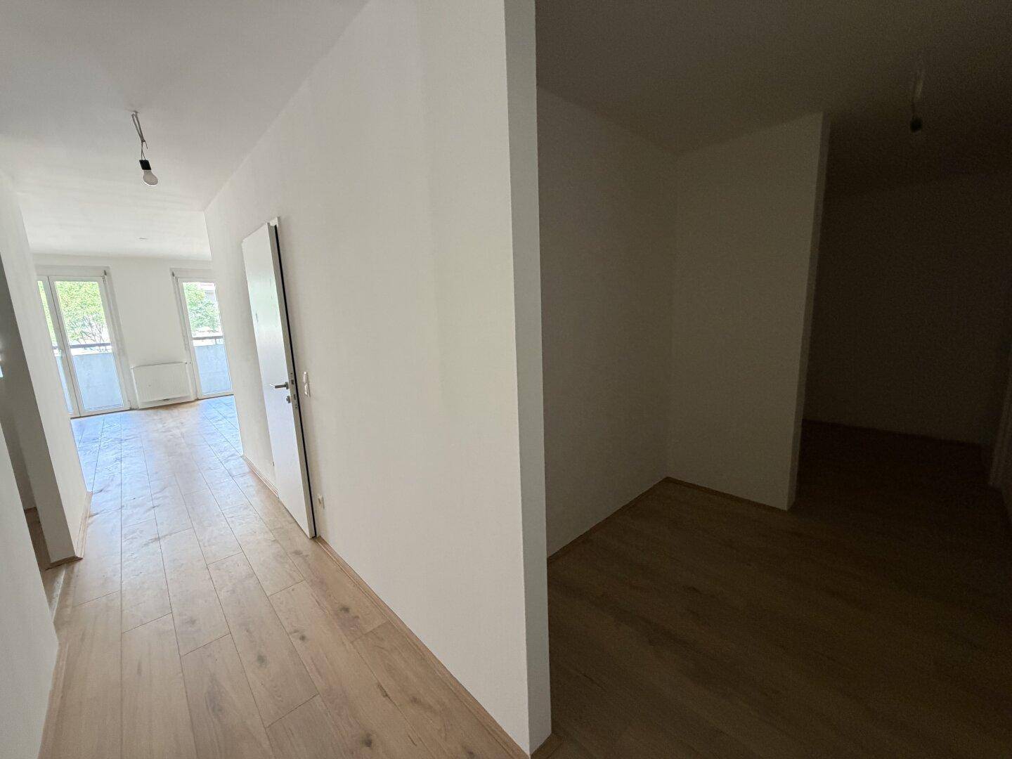Heller Flur mit Holzboden, der zu den Wohnbereichen führt und einladend wirkt.
