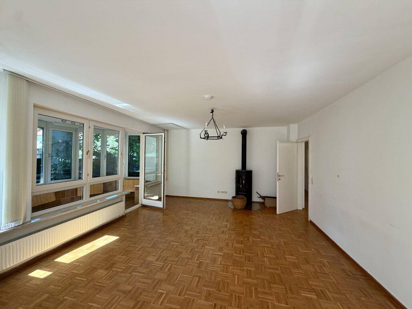 Geräumiges Wohnzimmer mit Parkettboden und einem gemütlichen Holzofen.