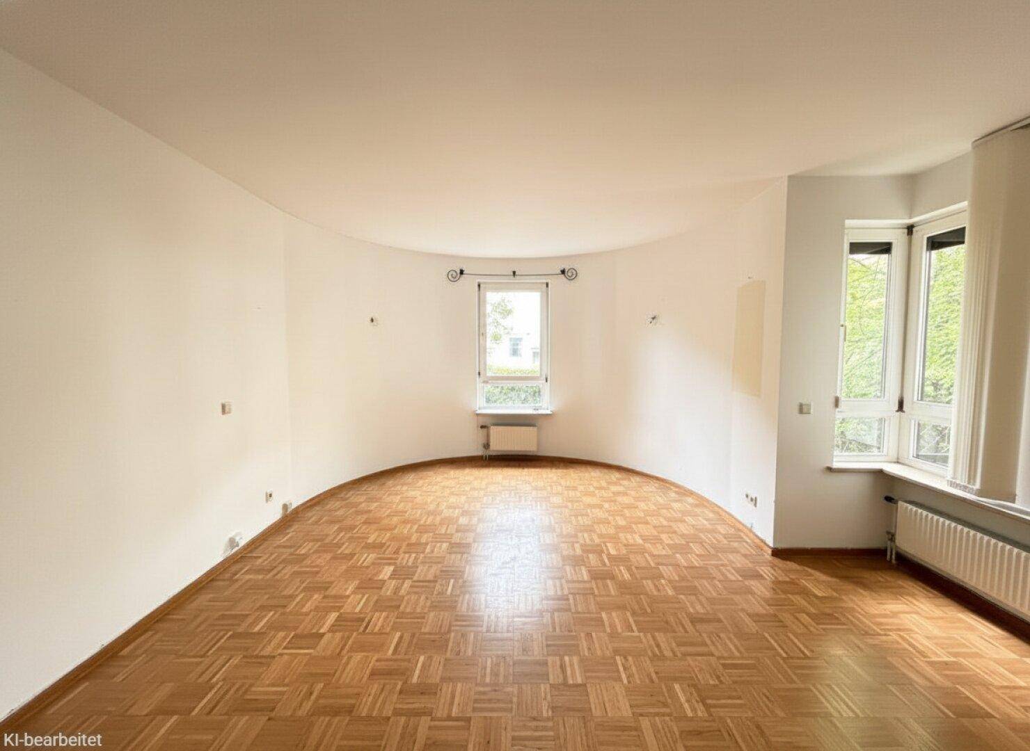 Lichtdurchflutetes Wohnzimmer mit einzigartiger geschwungener Wand und klassischem Parkettboden.