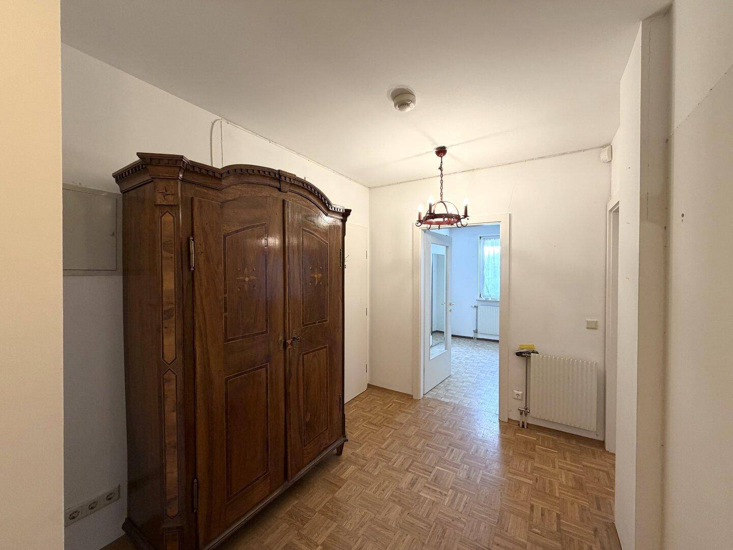 Heller Flur mit Parkettboden, Kronleuchter und Zugang zu weiteren Räumen.