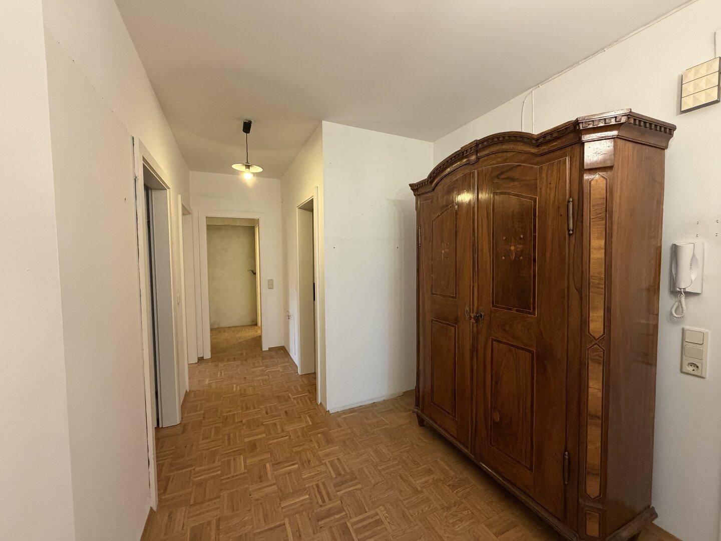 Flur mit klassischem Parkettboden und einem großen, antiken Holzschrank.
