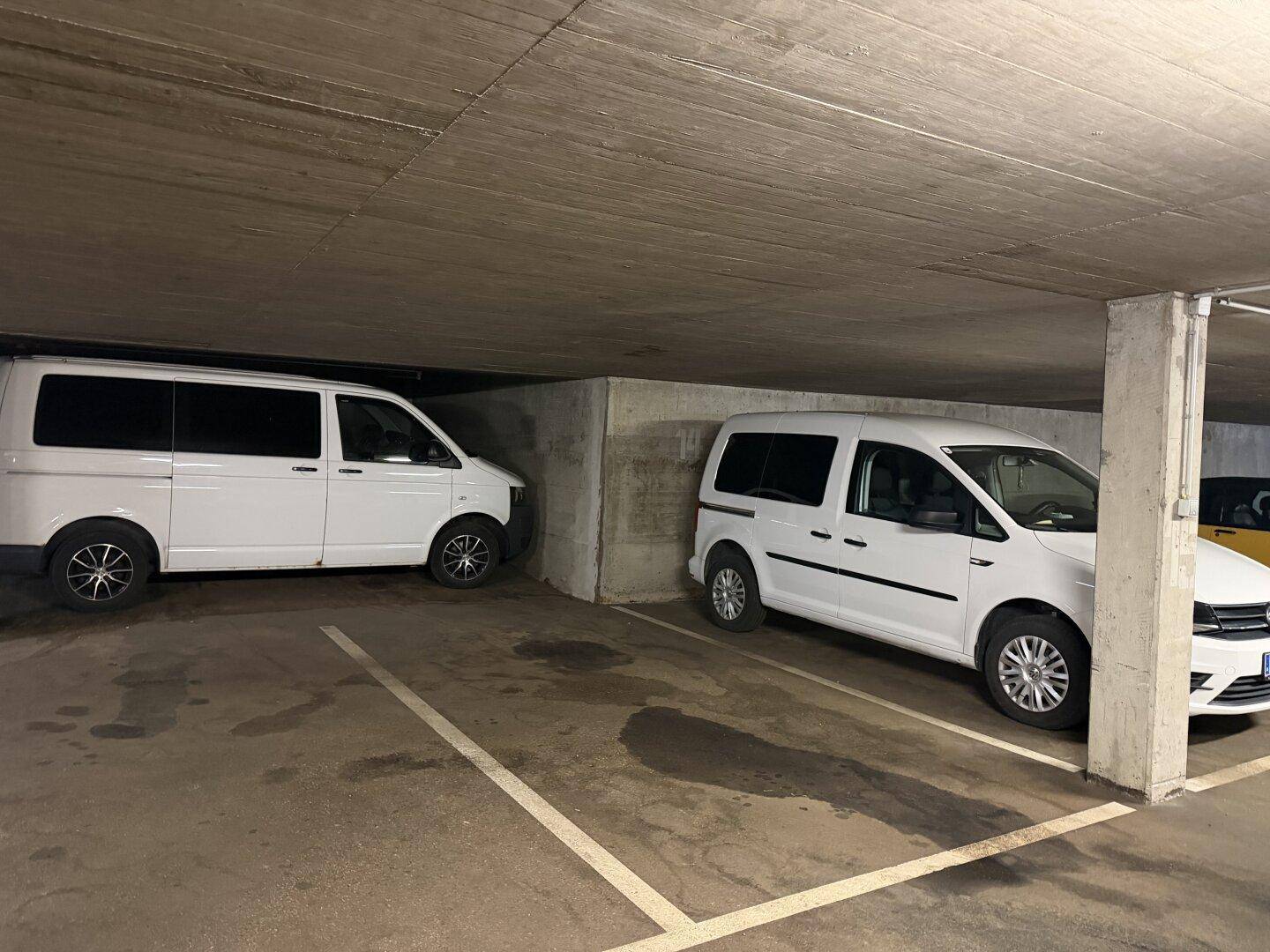 Tiefgarage mit zwei geparkten Fahrzeugen und Betonwänden.