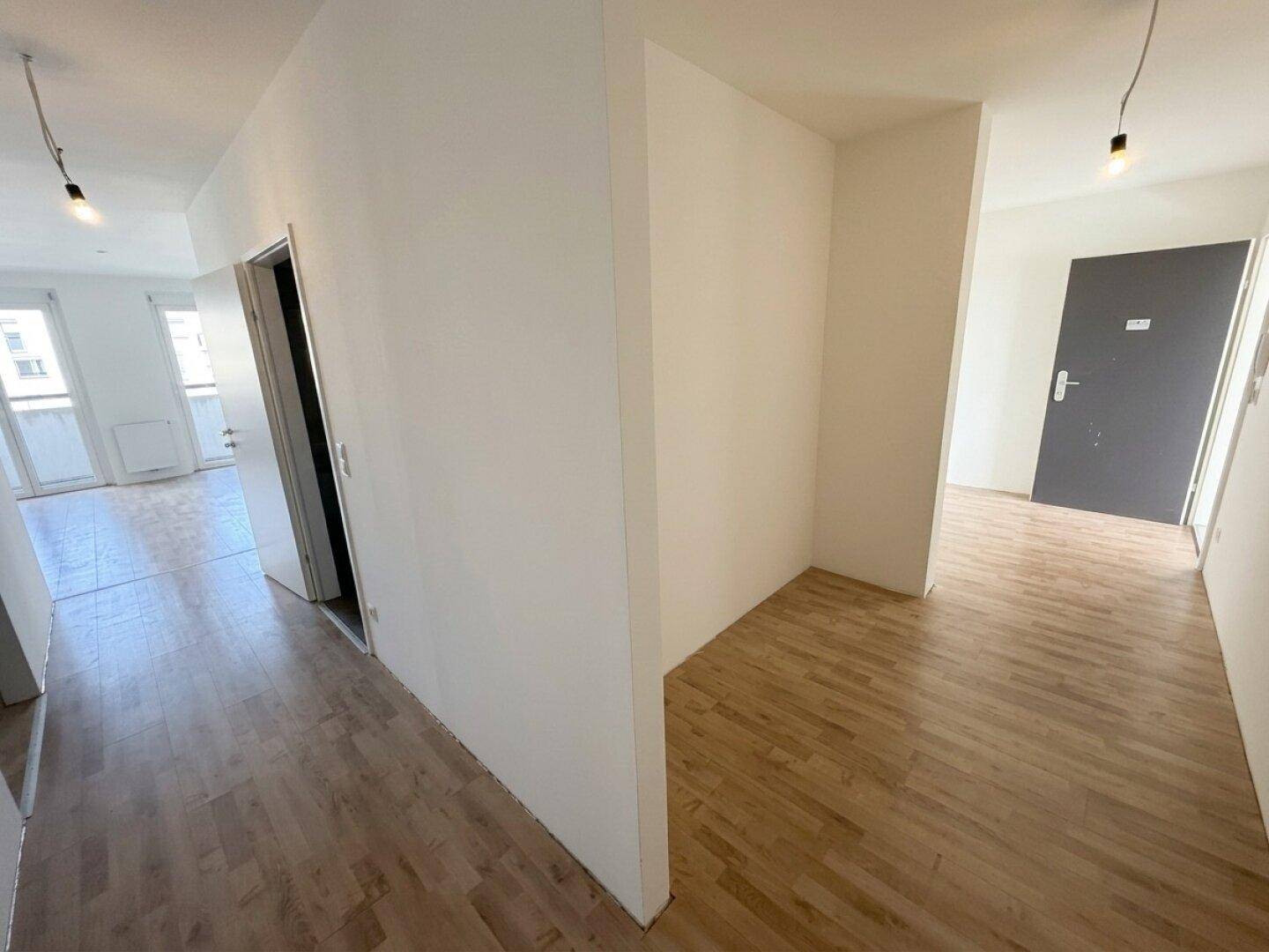 Heller Flur mit Laminatboden, der verschiedene Räume der Wohnung miteinander verbindet.