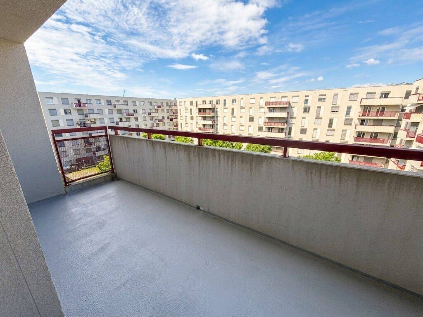 Geräumiger Balkon mit rotem Geländer und Blick auf die umliegenden Wohngebäude.