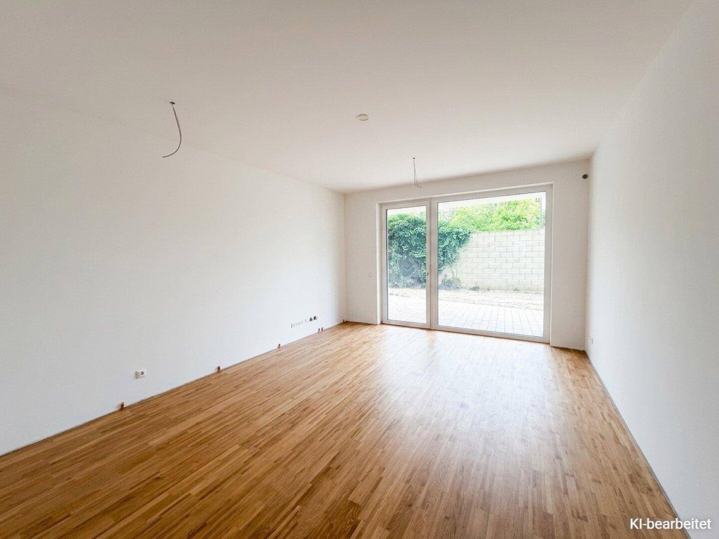 Heller, leerer Wohnraum mit hochwertigem Parkettboden und großem Zugang zur Terrasse.