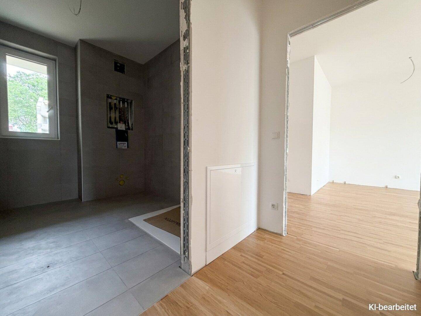 Modernes Badezimmer im Bau mit Fliesenboden und Duschbereich, angrenzend an einen weiteren Raum.