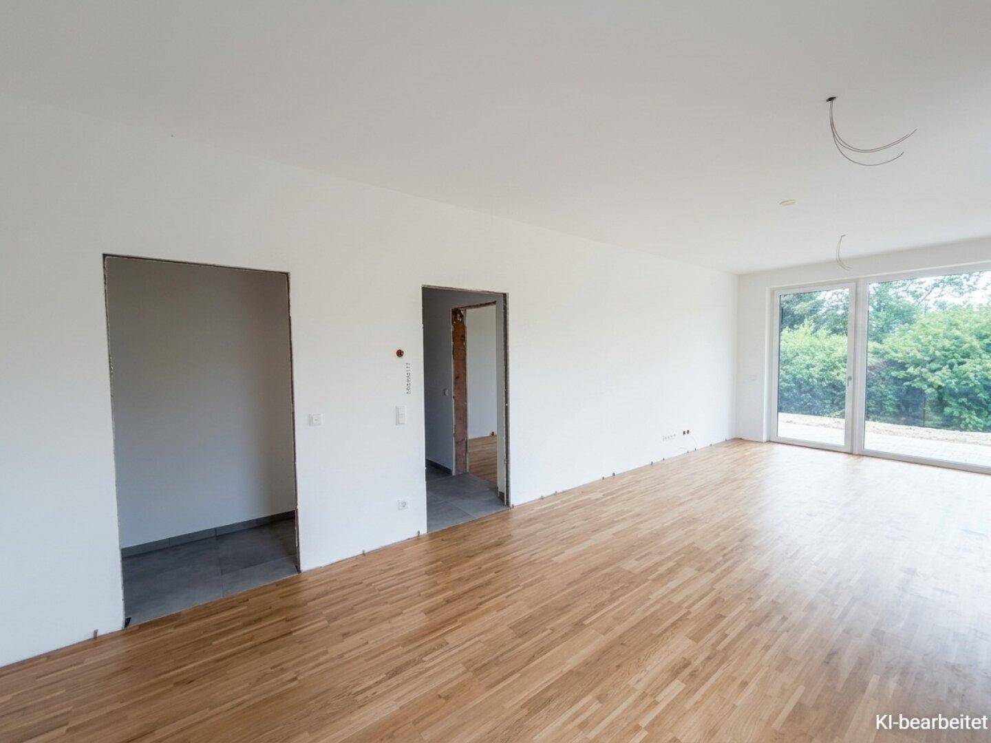 Unmöblierter Wohnraum mit hellem Holzboden, weißen Wänden und offenen Türrahmen zu angrenzenden Zimmern.