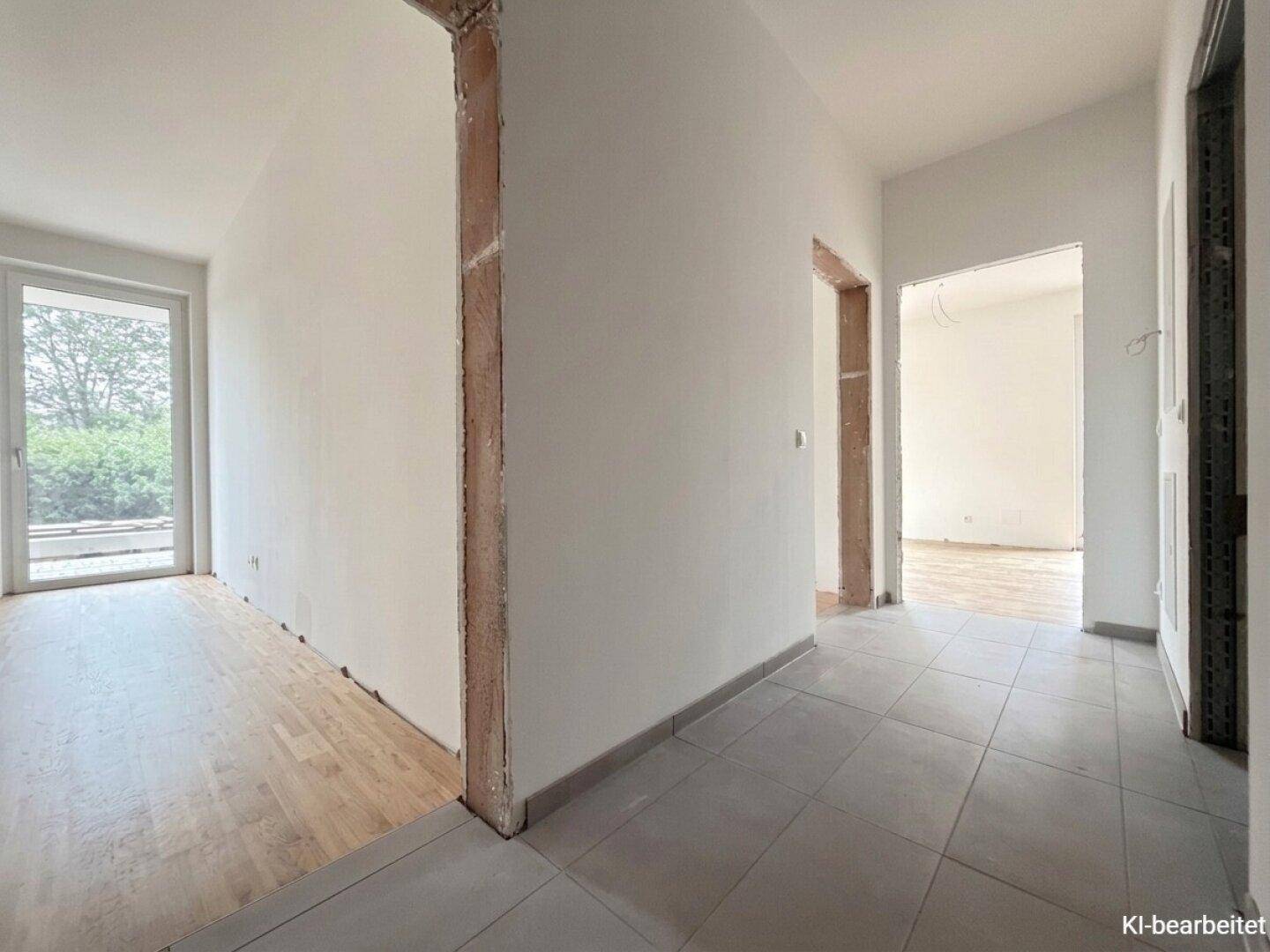 Heller Flurbereich mit Fliesen- und Holzboden, der zu weiteren Räumen des Neubaus führt.