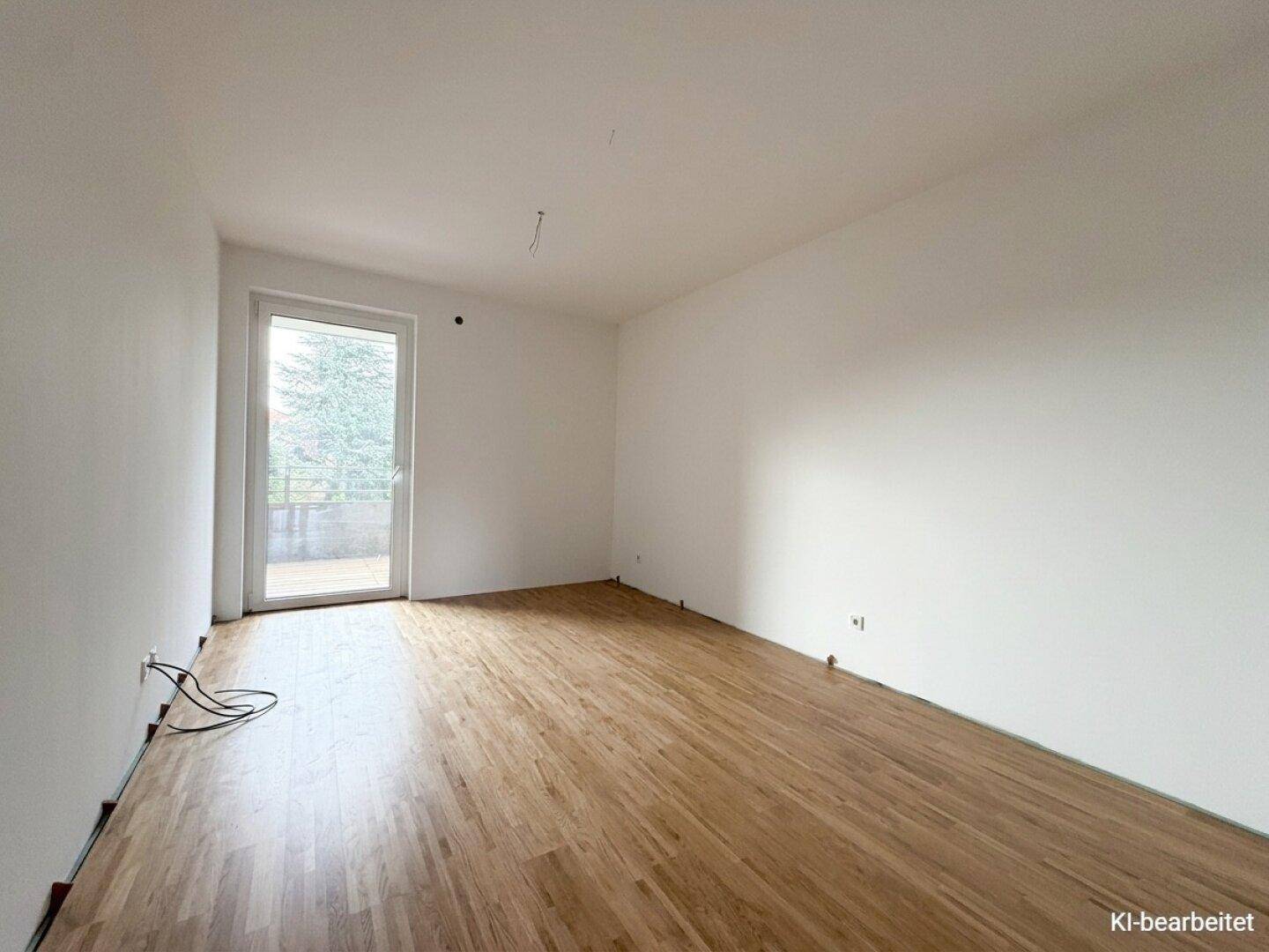 Leeres Zimmer mit Holzboden und Zugang zu einem Außenbereich, bereit für individuelle Gestaltung.