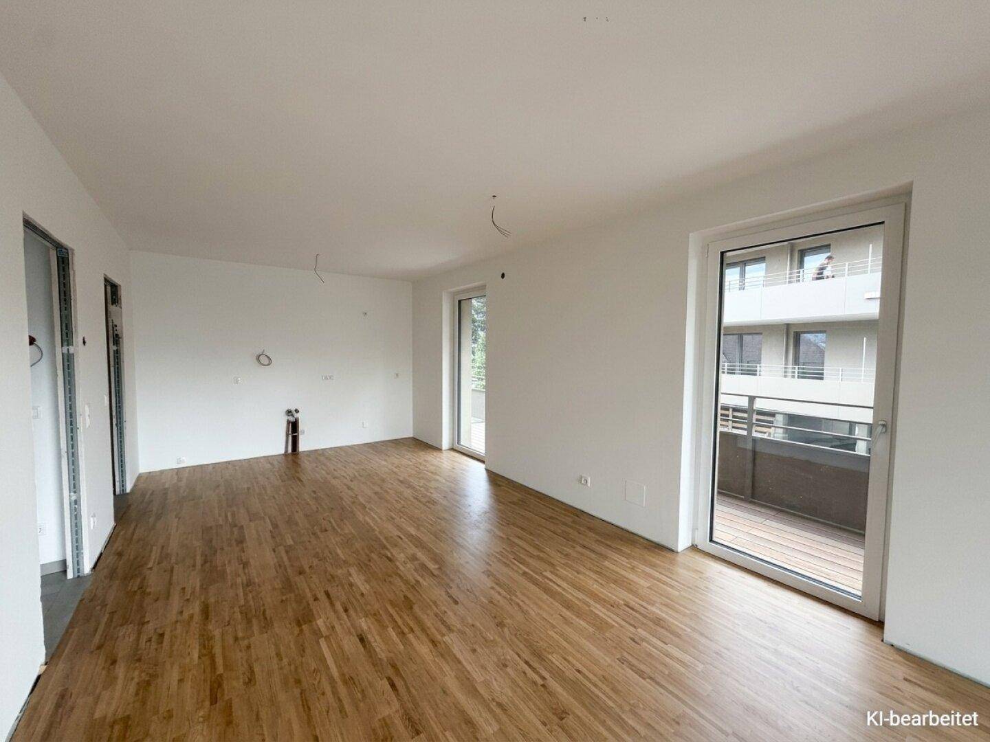 Heller, leerer Raum mit Holzboden und Zugang zu einem Balkon, ideal für einen Wohnbereich.