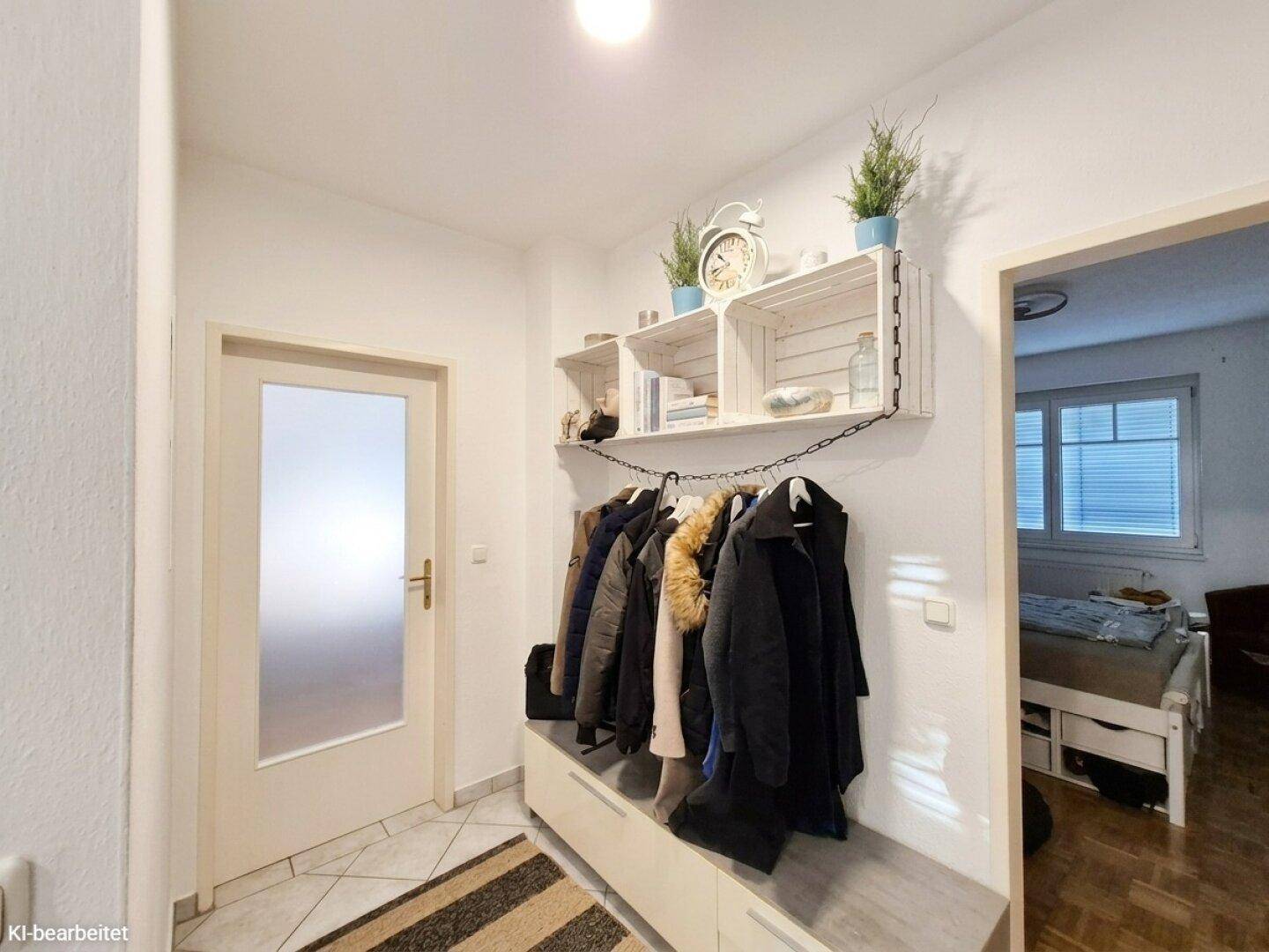 Eingangsbereich mit Garderobe, Schuhschrank und hellen Fliesen, führt zu weiteren Räumen.