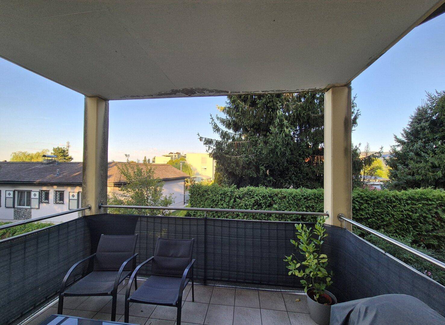 Geräumiger Balkon mit Sitzmöbeln und weitem Blick über die grüne Nachbarschaft.