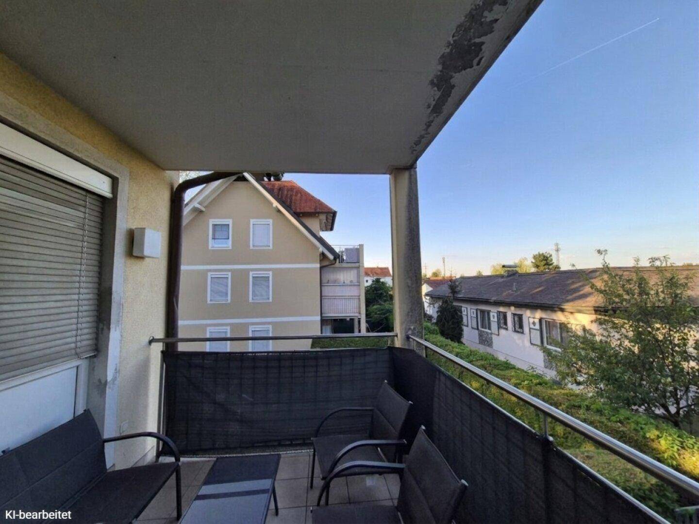 Balkon mit Sitzgelegenheiten und Blick auf die umliegenden Wohnhäuser und Gärten.