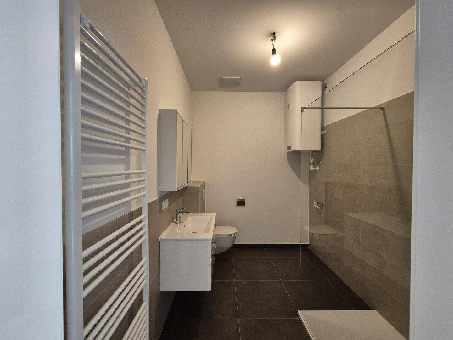 Modernes Badezimmer mit Dusche, Waschbecken und beheiztem Handtuchhalter.