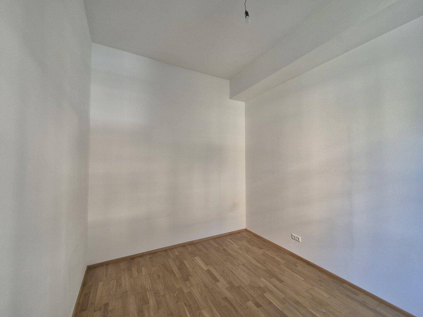 Leerer Raum mit hellen Wänden und Parkettboden, bereit zur individuellen Gestaltung.