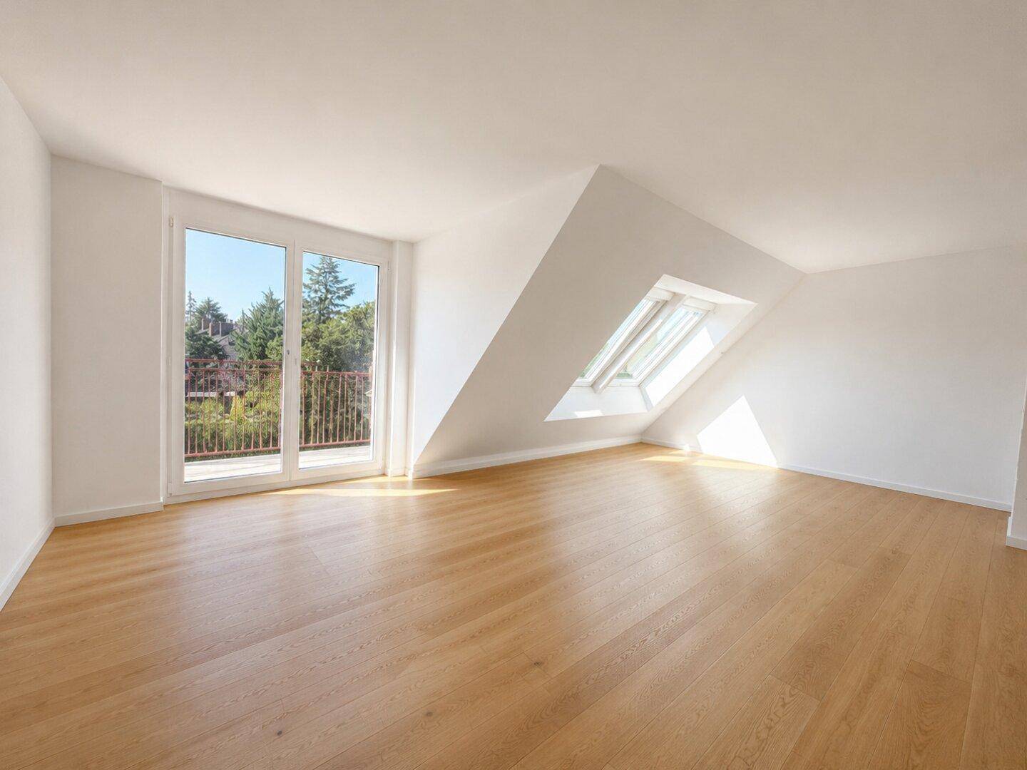 Leeres Schlafzimmer im Dachgeschoss mit Holzboden, Dachfenstern und Balkonzugang, hell und geräumig.