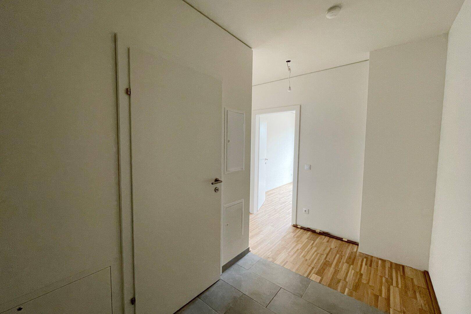 Eingangsbereich mit Fliesenboden, der in Parkett übergeht, und weißen Türen.