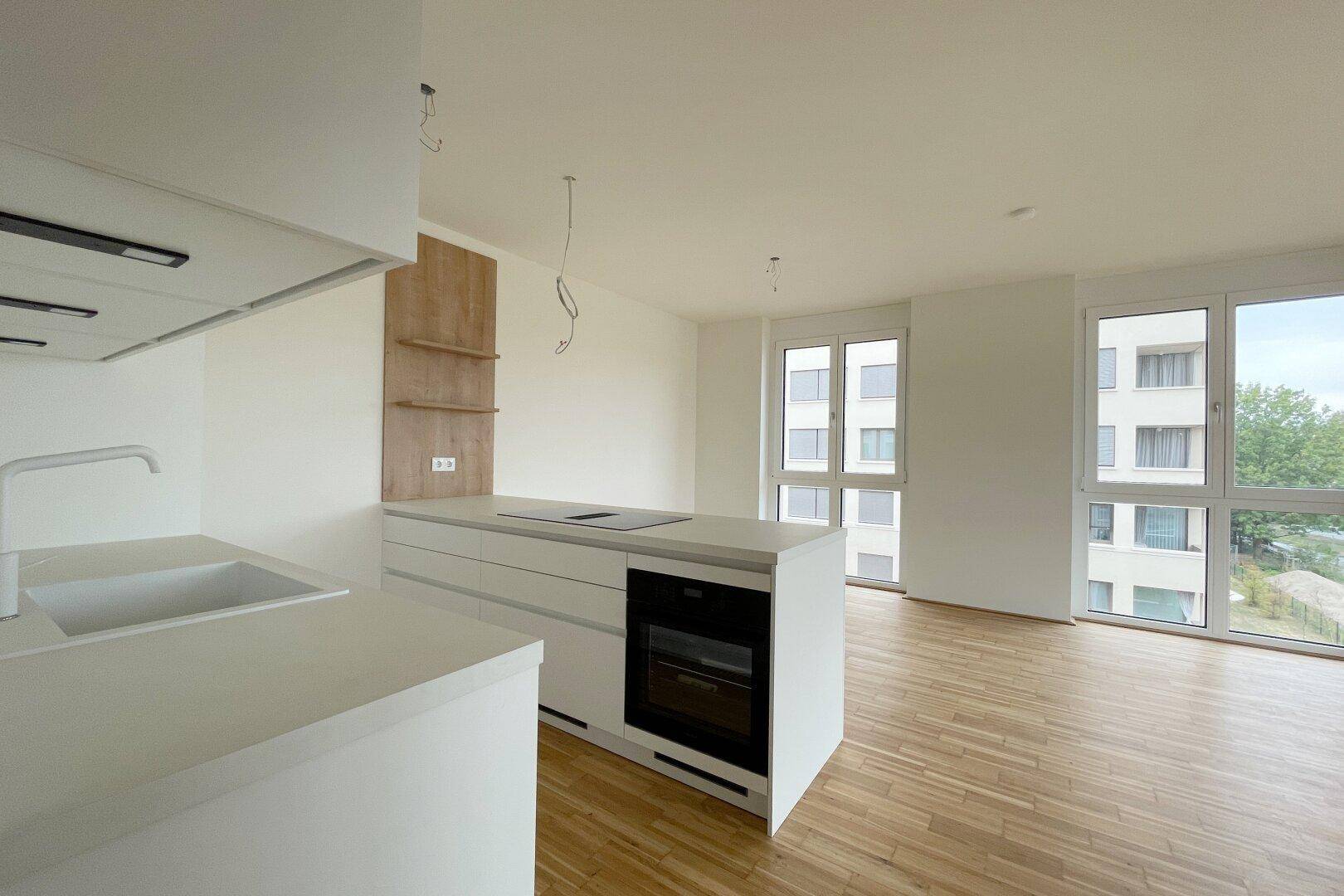 Moderne Einbauküche mit weißer Kücheninsel, Induktionskochfeld und integriertem Backofen.