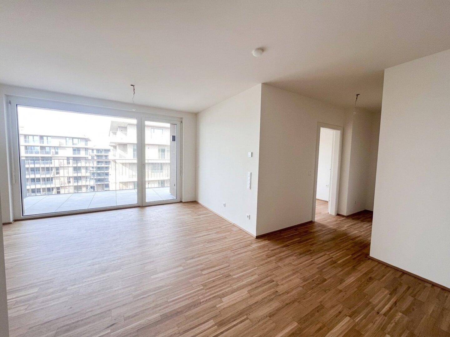 Geräumiger, heller Raum mit Parkettboden und großen Fenstern mit direktem Zugang zum Balkon.