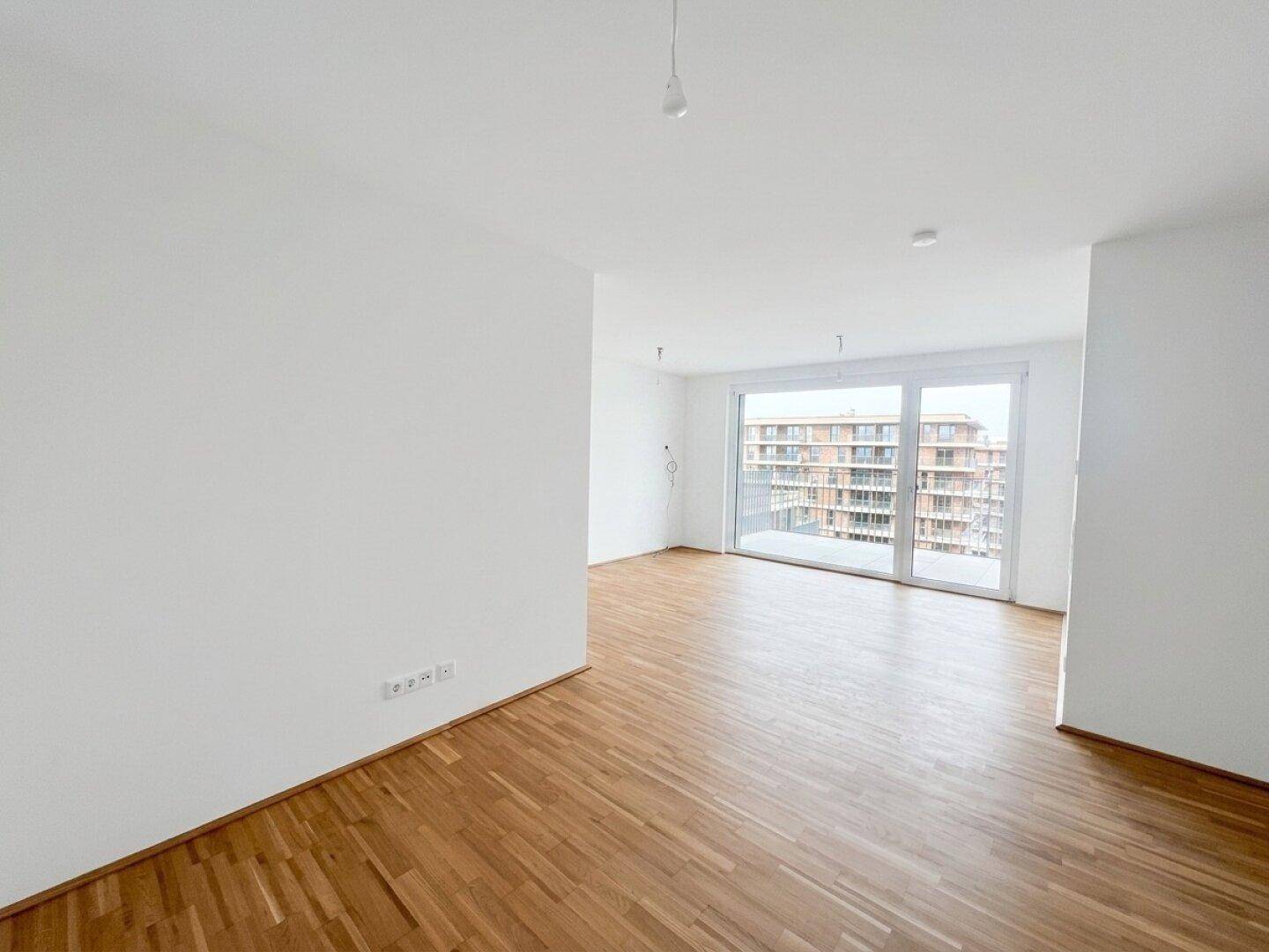 Lichtdurchfluteter Wohnbereich mit Holzparkett und weiten Ausblicken durch die großen Fensterfronten.