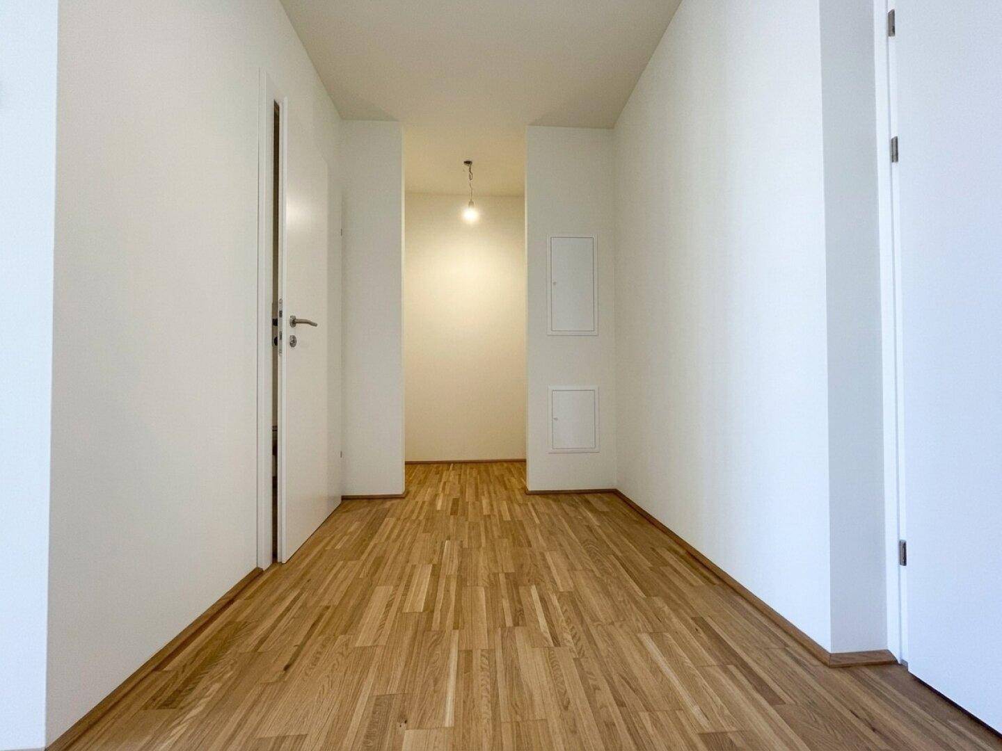 Heller Flur mit Parkettboden und weißen Türen, der zu weiteren Räumen der Wohnung führt.